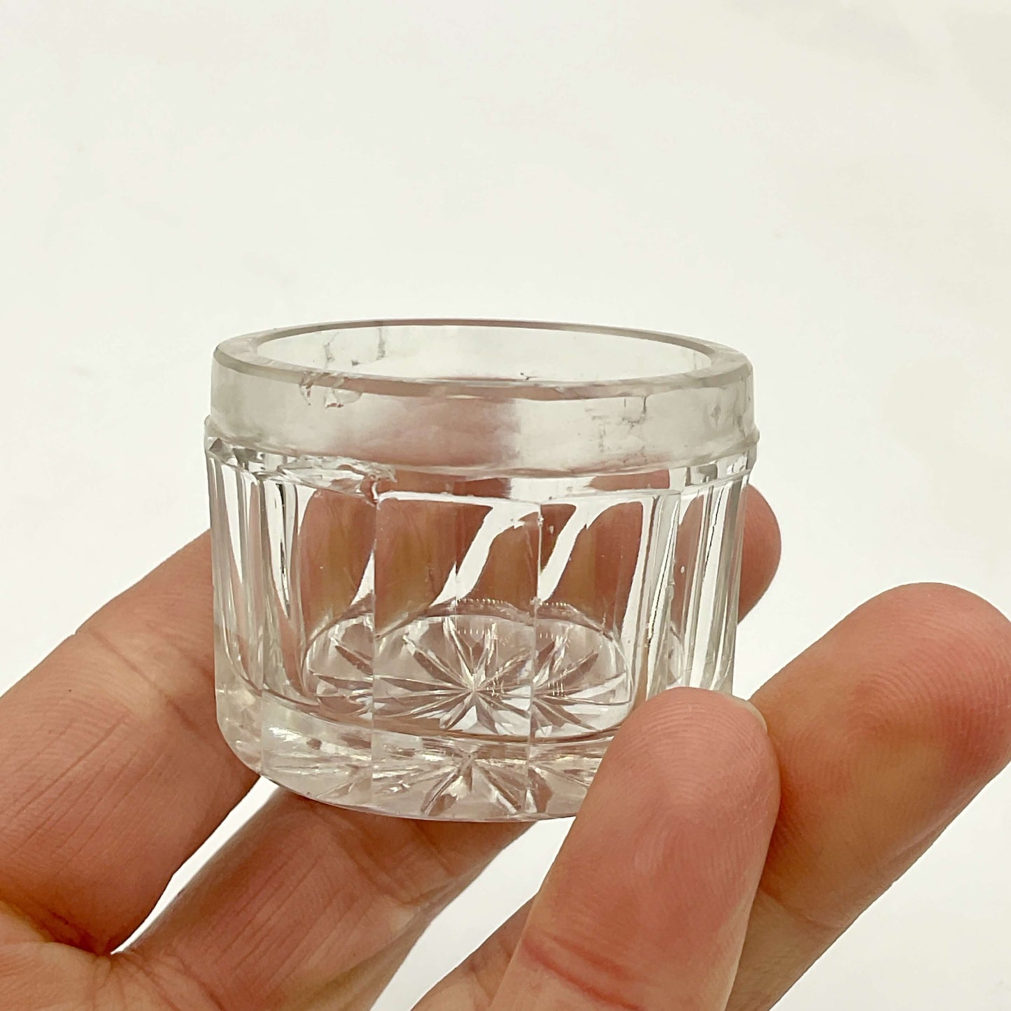 Clear glass jar held in a hand against a plain background