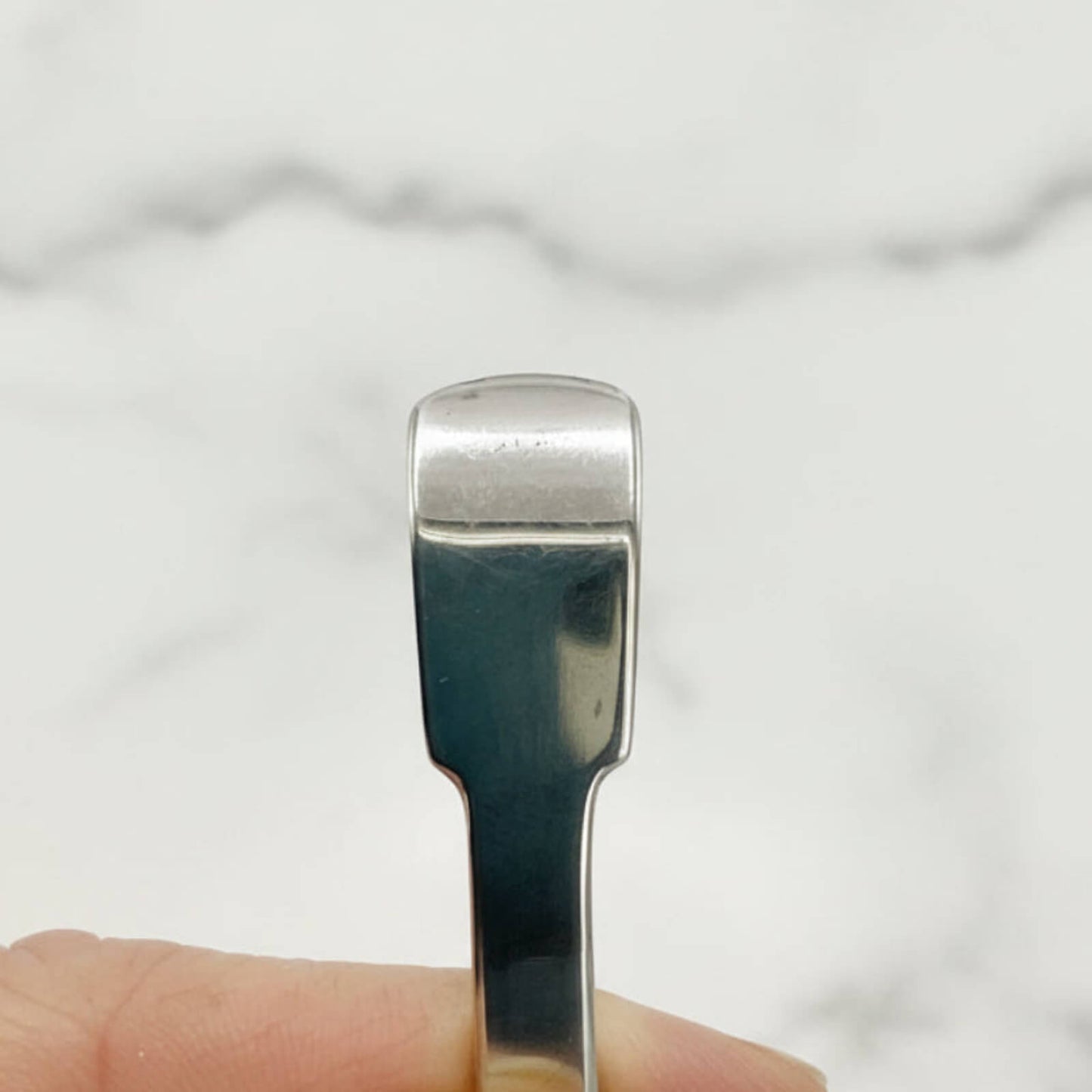 Silver spoon handle held by a hand against a white background