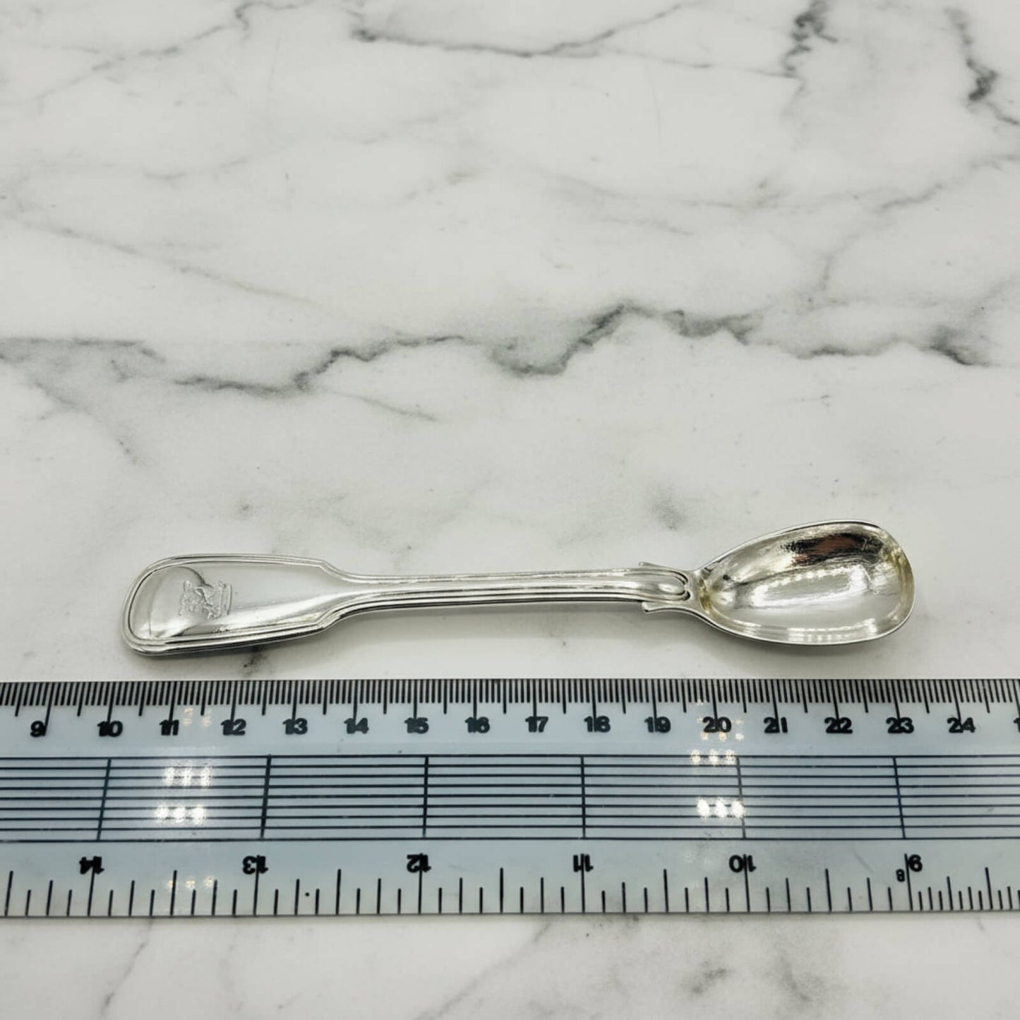 Antique 1835 Sterling Silver Mustard Spoon next to a ruler on marble