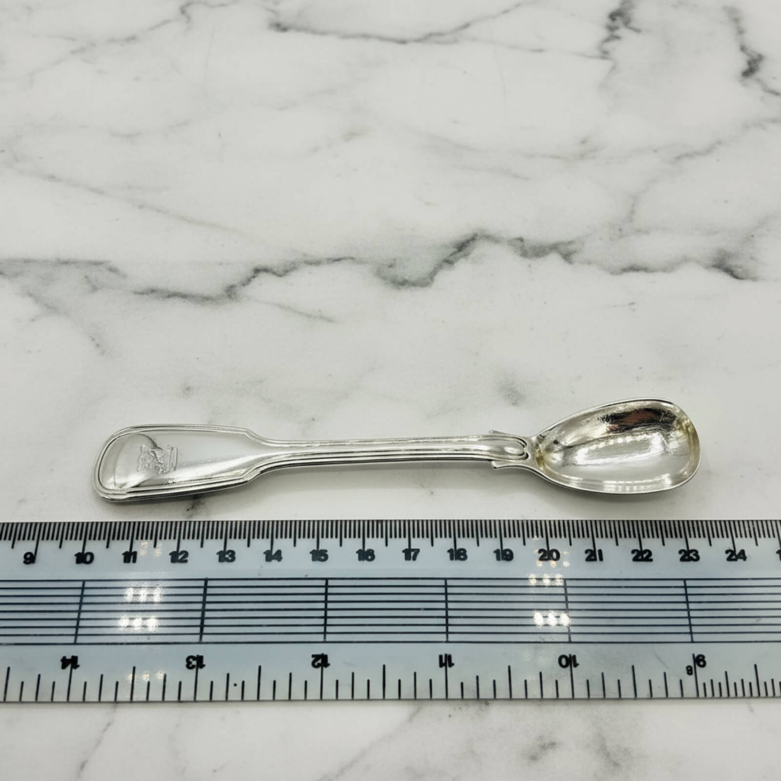 Antique 1835 Sterling Silver Mustard Spoon next to a ruler on marble