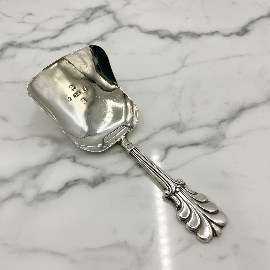 Silver caddy spoon on a marble surface