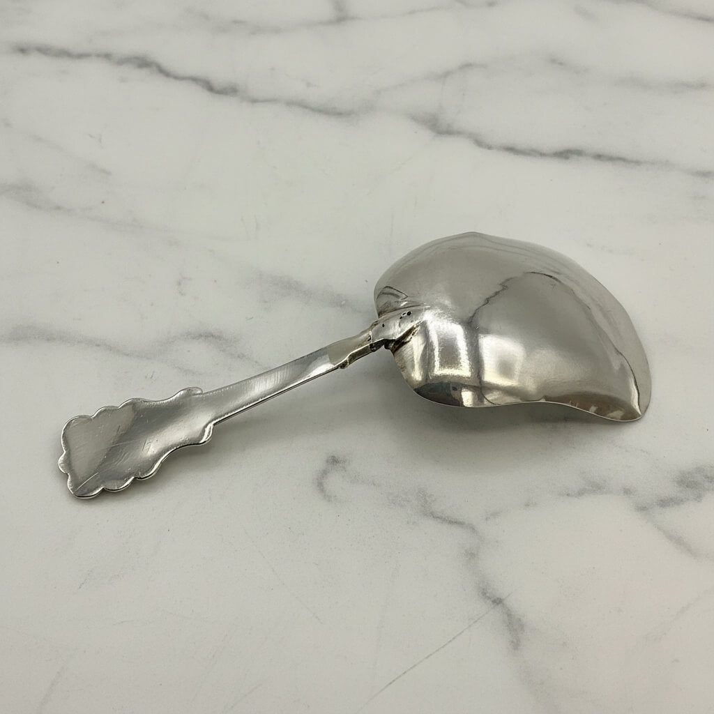 Silver caddy spoon upside down on a marble surface