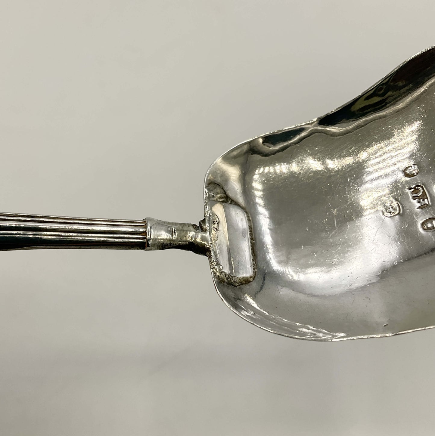 close up of silver caddy spoon handle with a repair on a white background