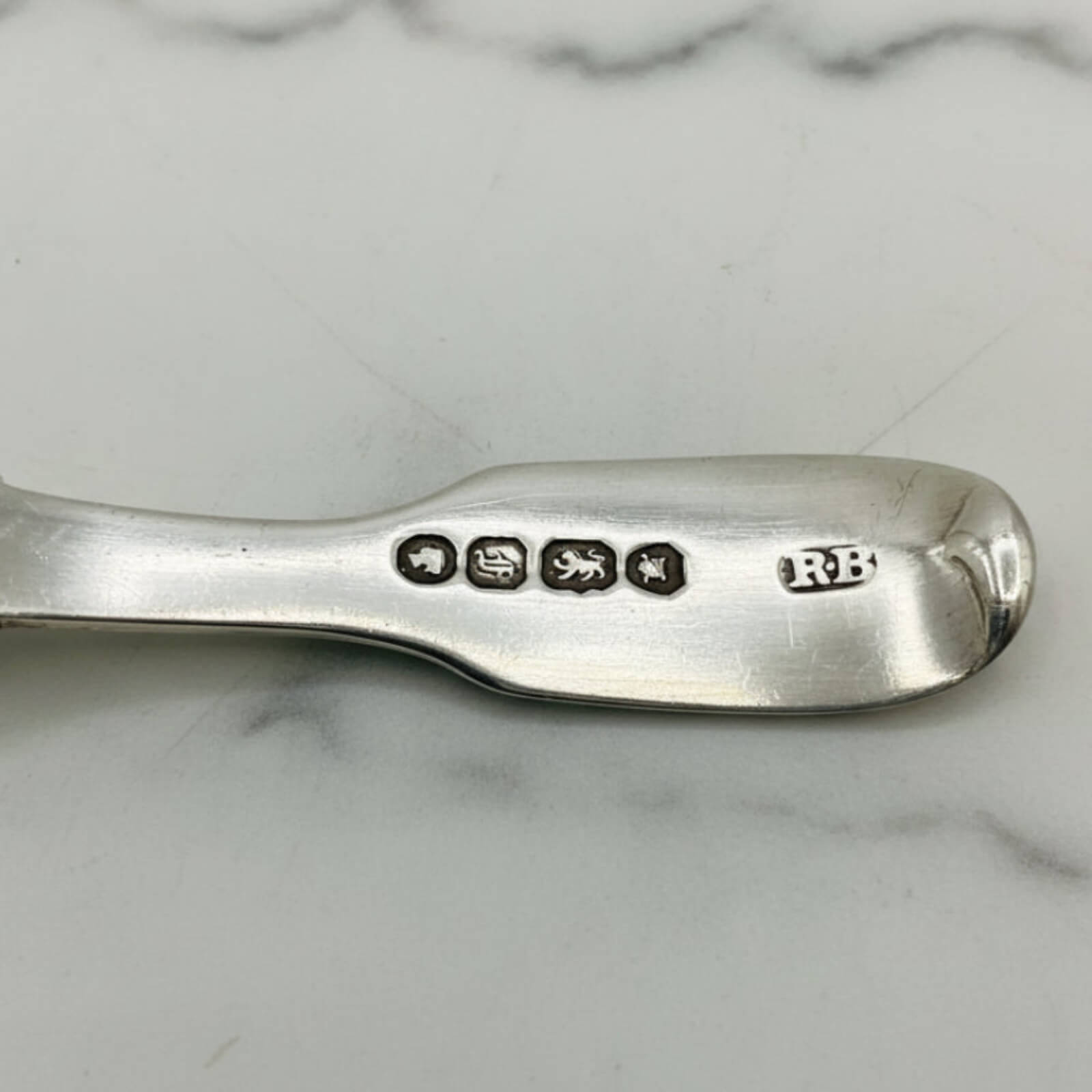 Silver spoon with hallmarks on a marble surface
