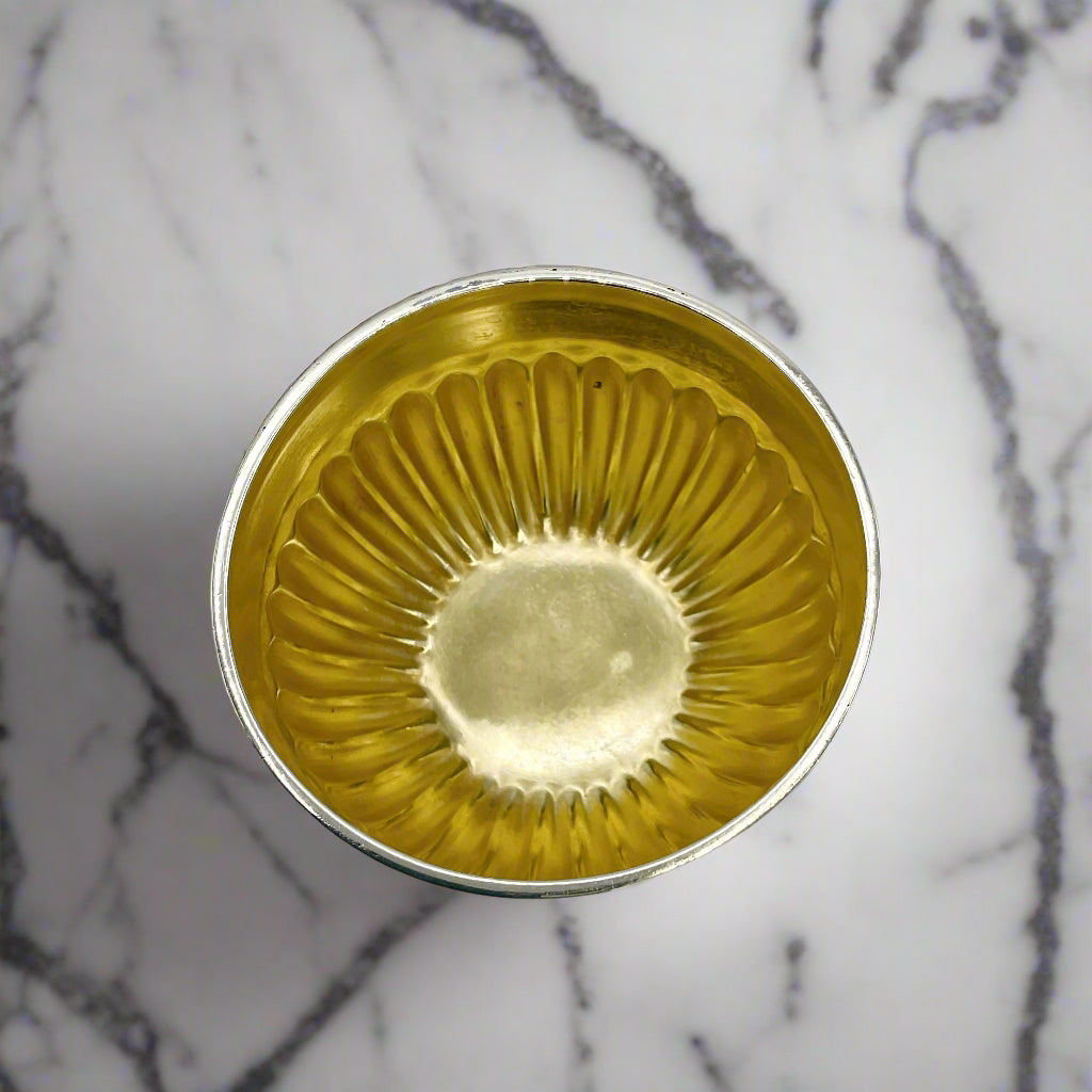 Inside of gilded Victorian silver salt on a marble worktop