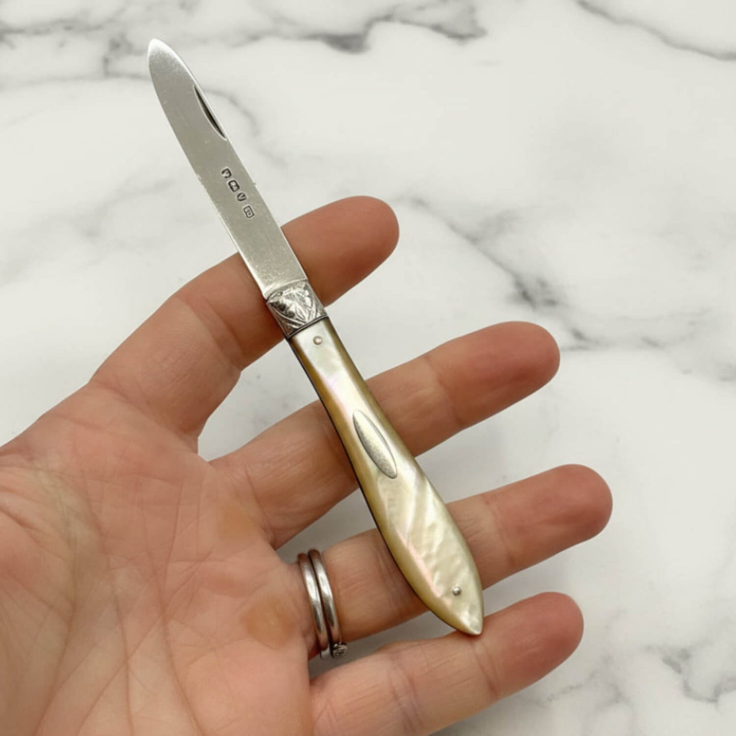 Hand holding a decorative knife with a marble background