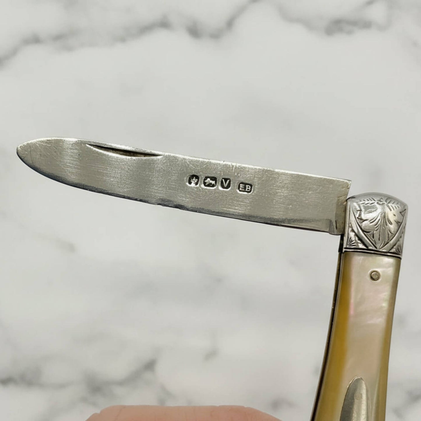 Close-up of a folding knife with decorative handle on a marble background