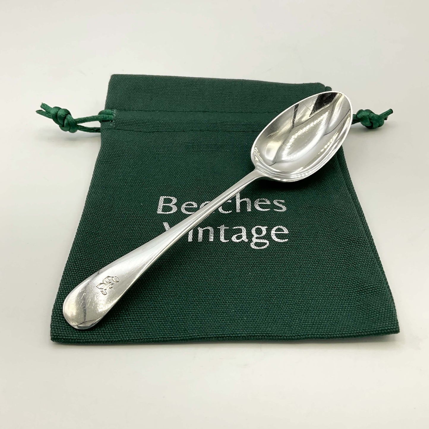 Antique silver teaspoon on a green gift bag and a white background 