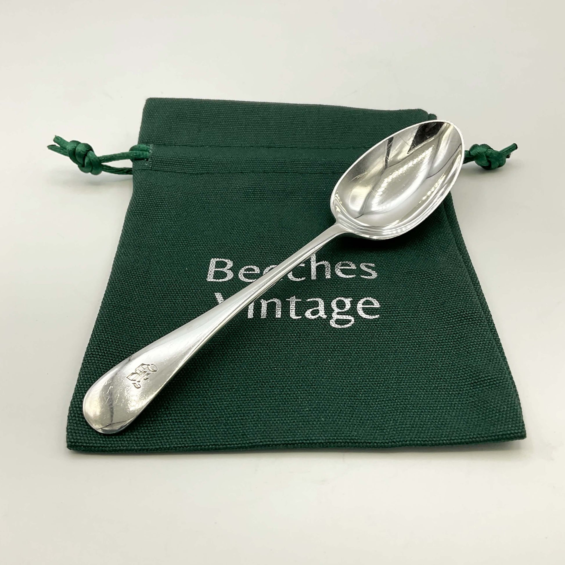 Antique silver teaspoon on a green gift bag and a white background 