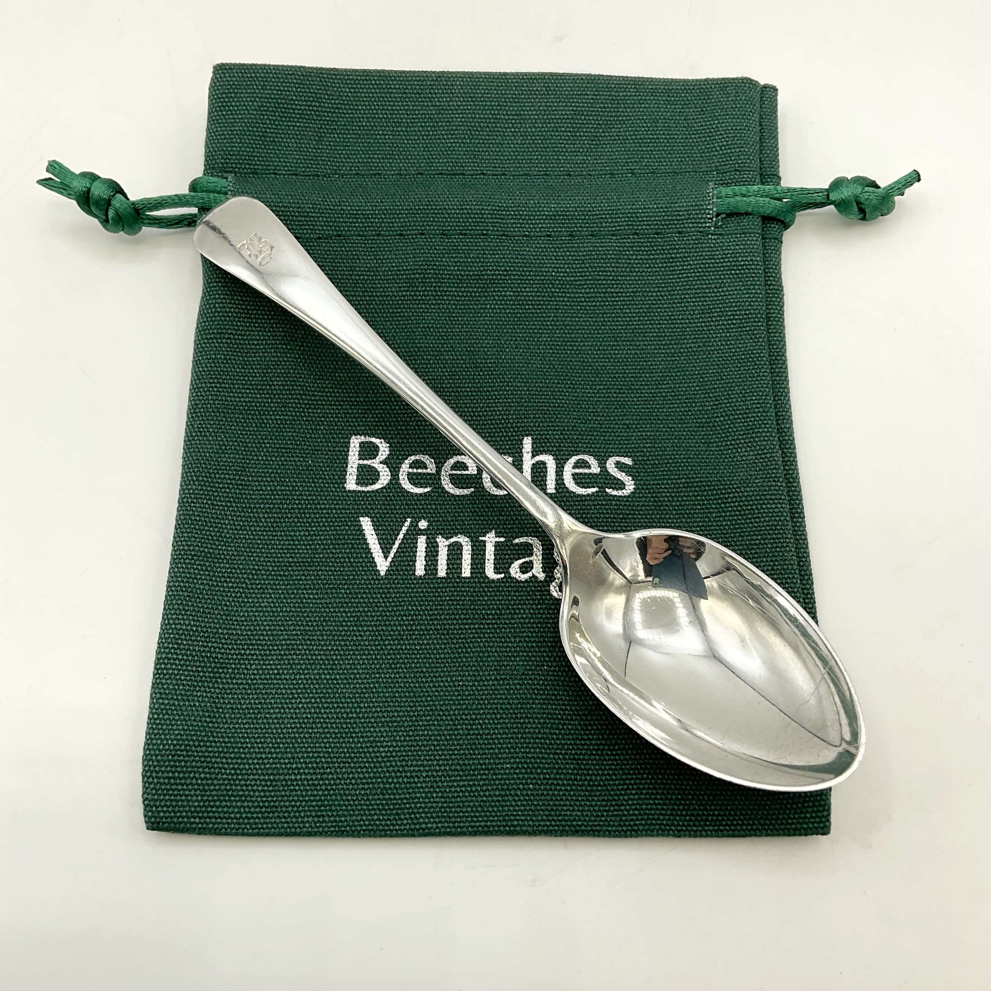 Antique silver teaspoon on a green gift bag and a white background 