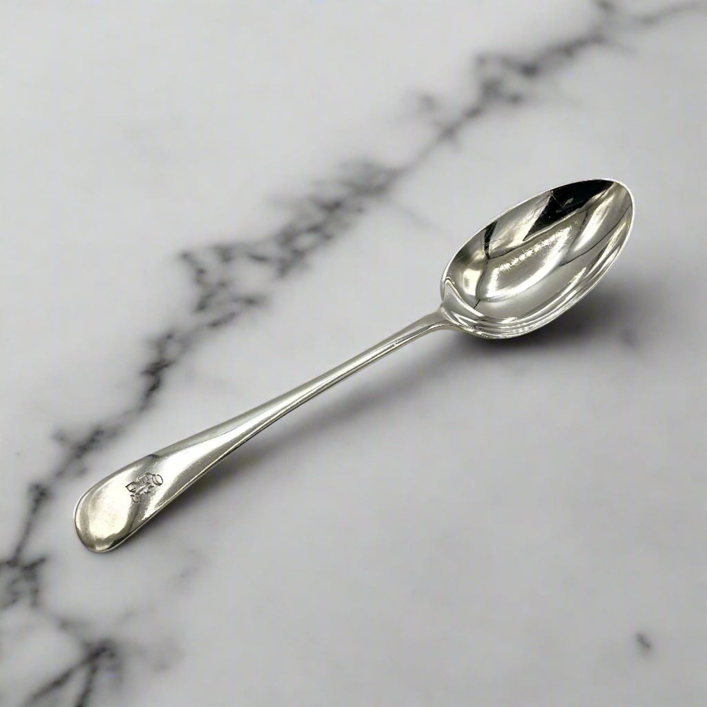 Antique silver teaspoon on a white marble worktop