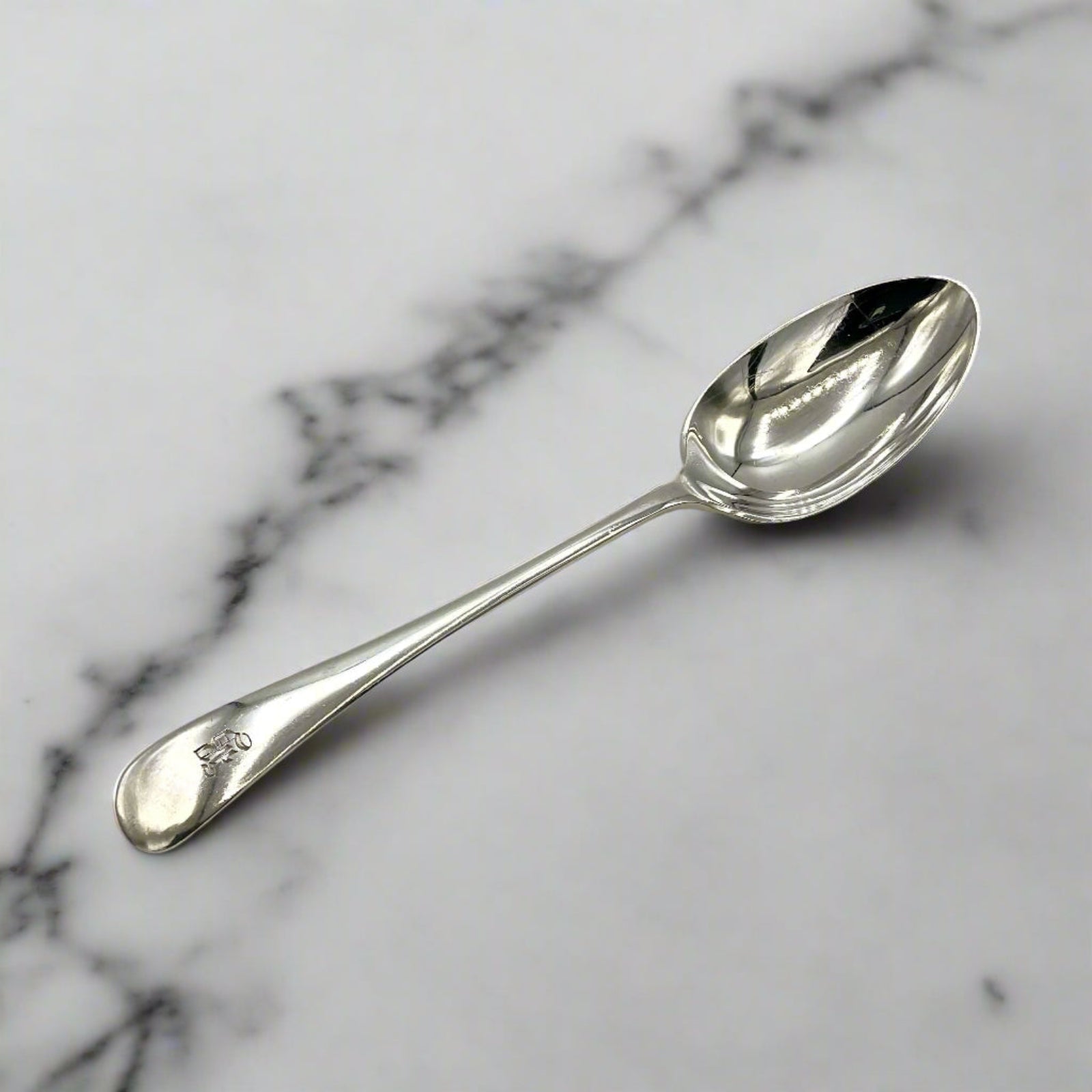 Antique silver teaspoon on a white marble worktop