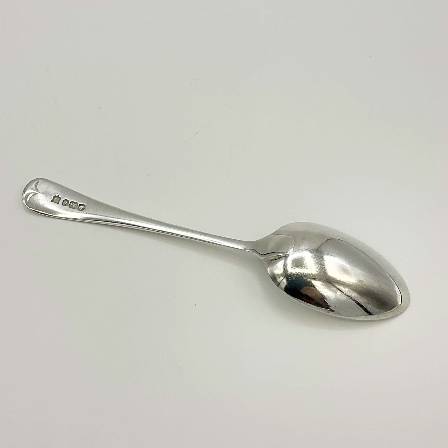 The back of a Antique silver teaspoon on a white background 