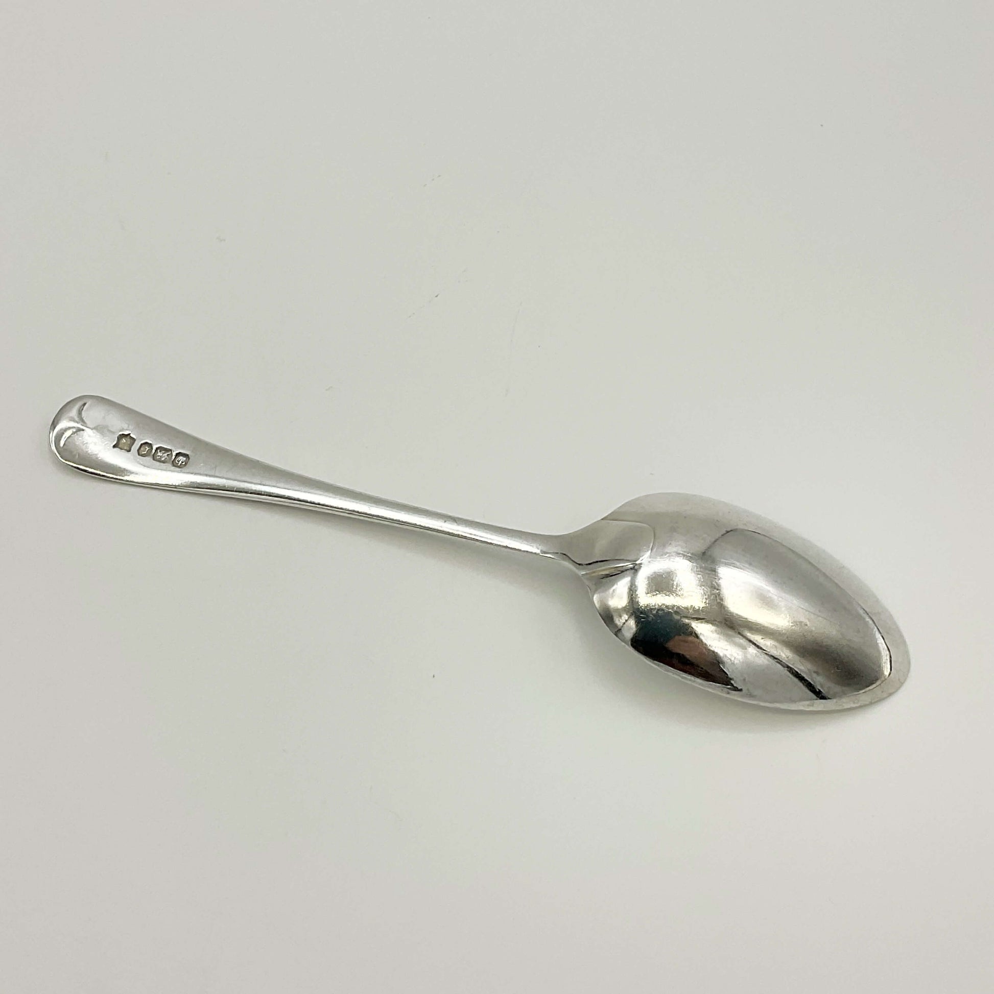 The back of a Antique silver teaspoon on a white background 