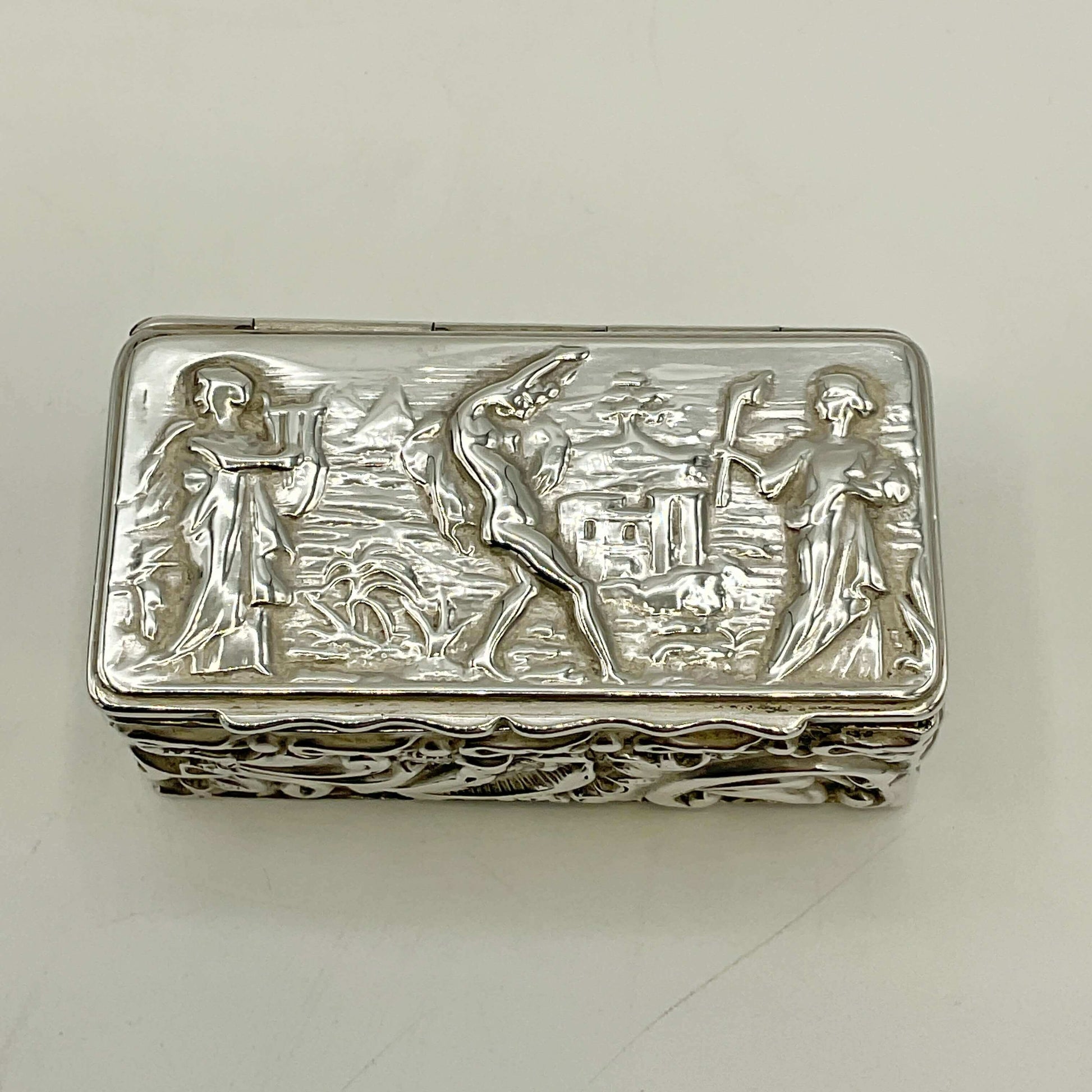Silver decorative box with embossed figures on a white background
