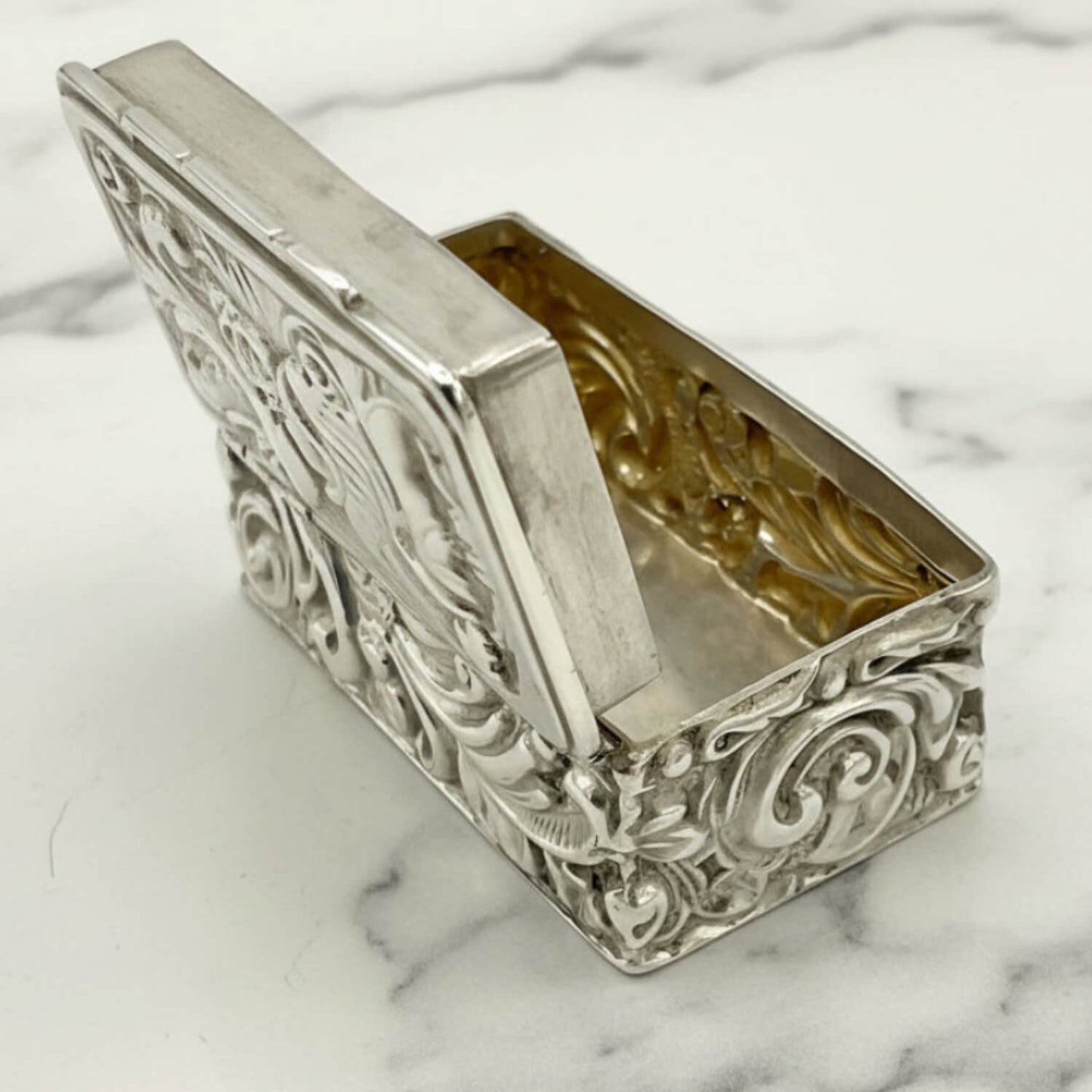 Decorative silver box with intricate designs on a marble surface