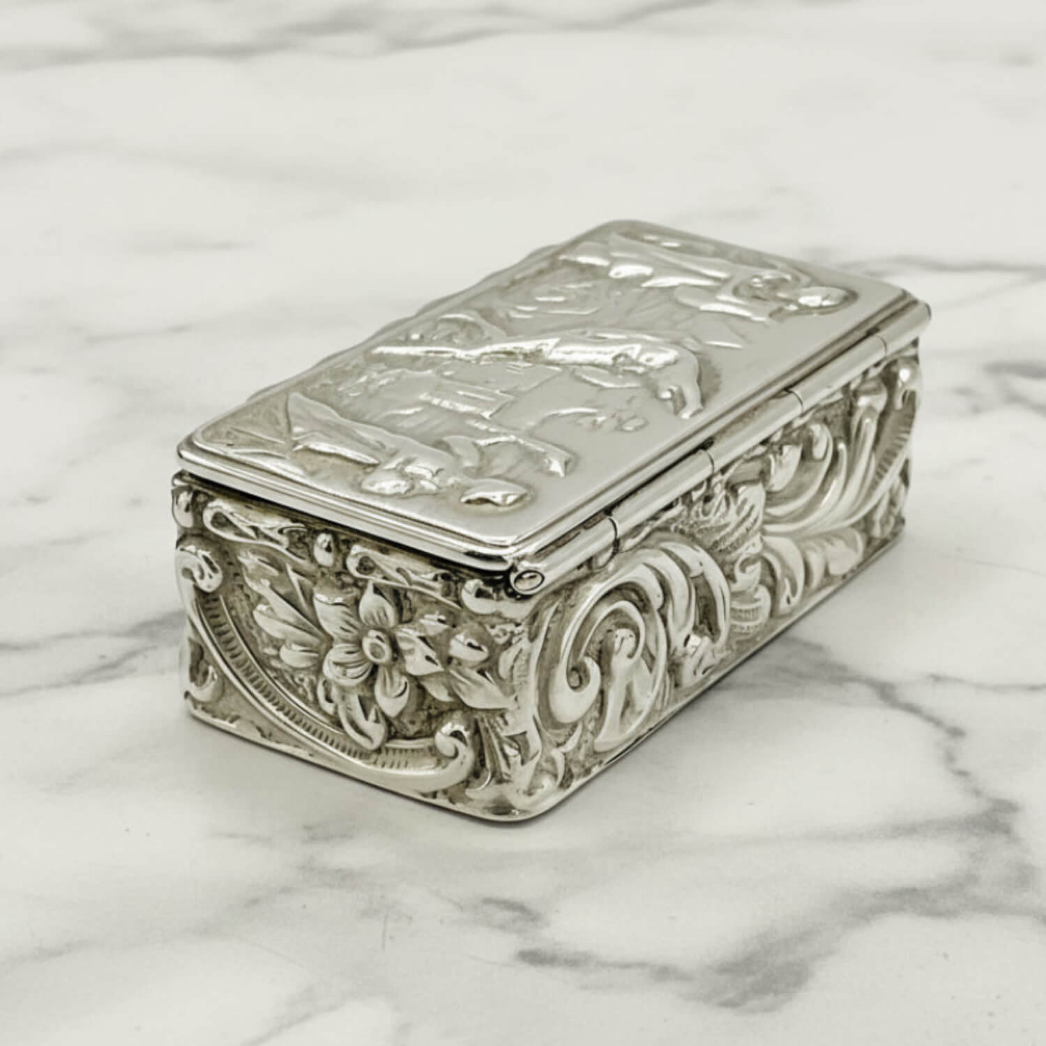 Decorative silver box with intricate designs on a marble surface