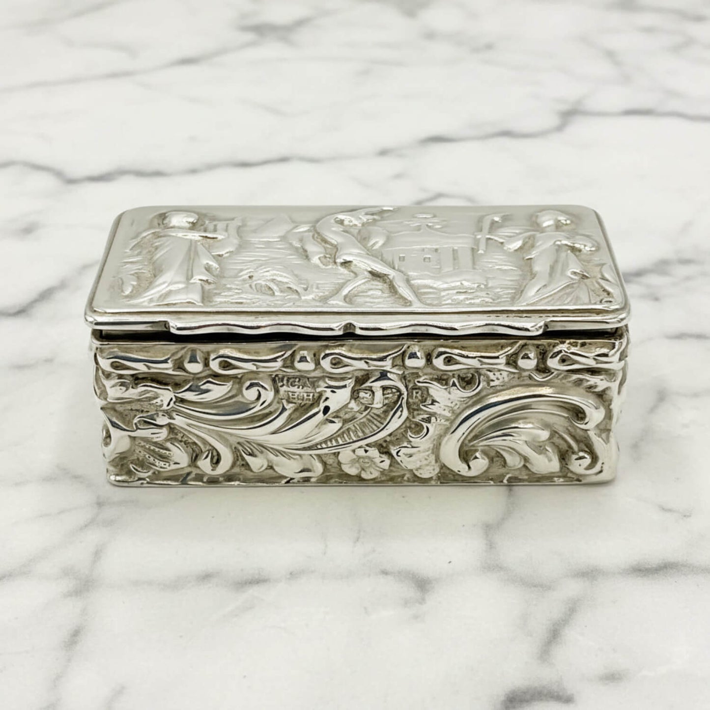 Decorative silver box with intricate designs on a marble surface