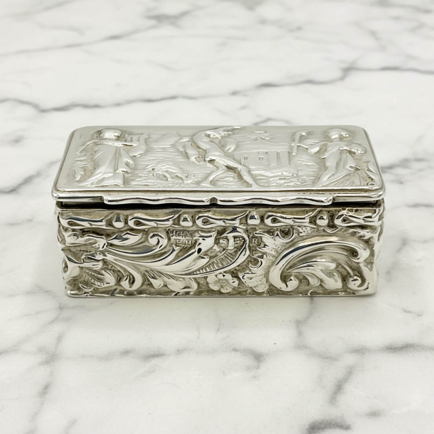 Decorative silver box with intricate designs on a marble surface