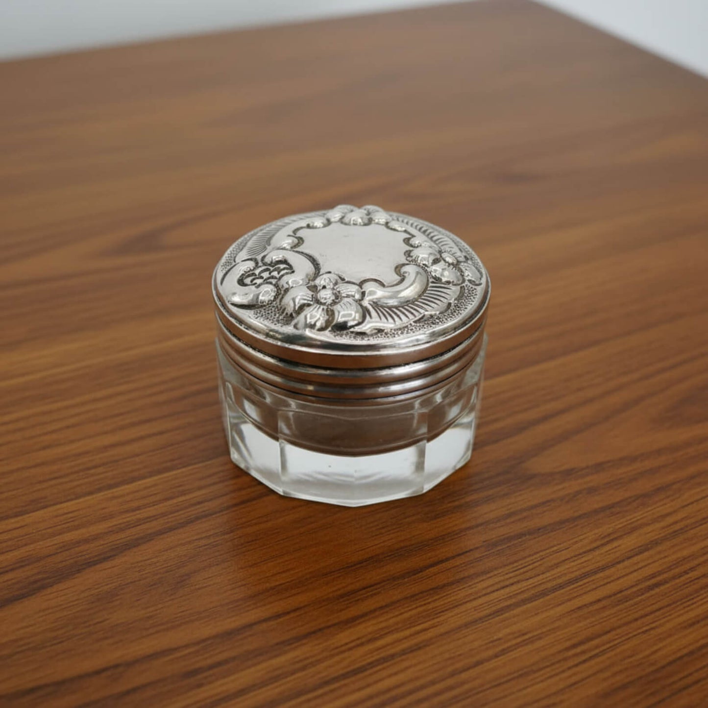 Decorative glass jar with silver lid on a wooden surface