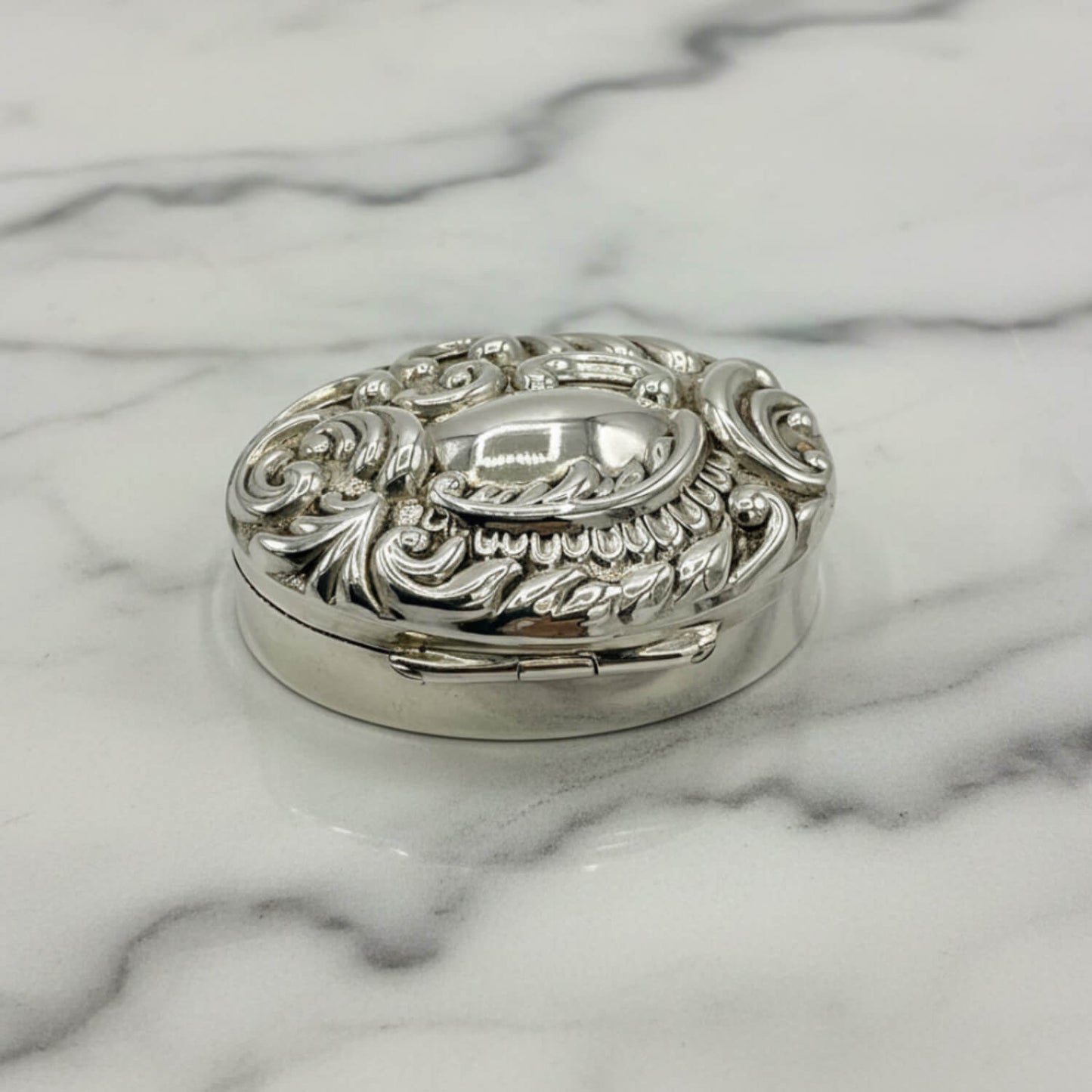Decorative silver pill box on a marble surface
