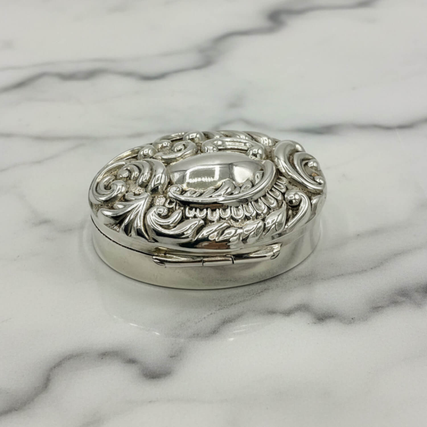 Decorative silver pill box on a marble surface
