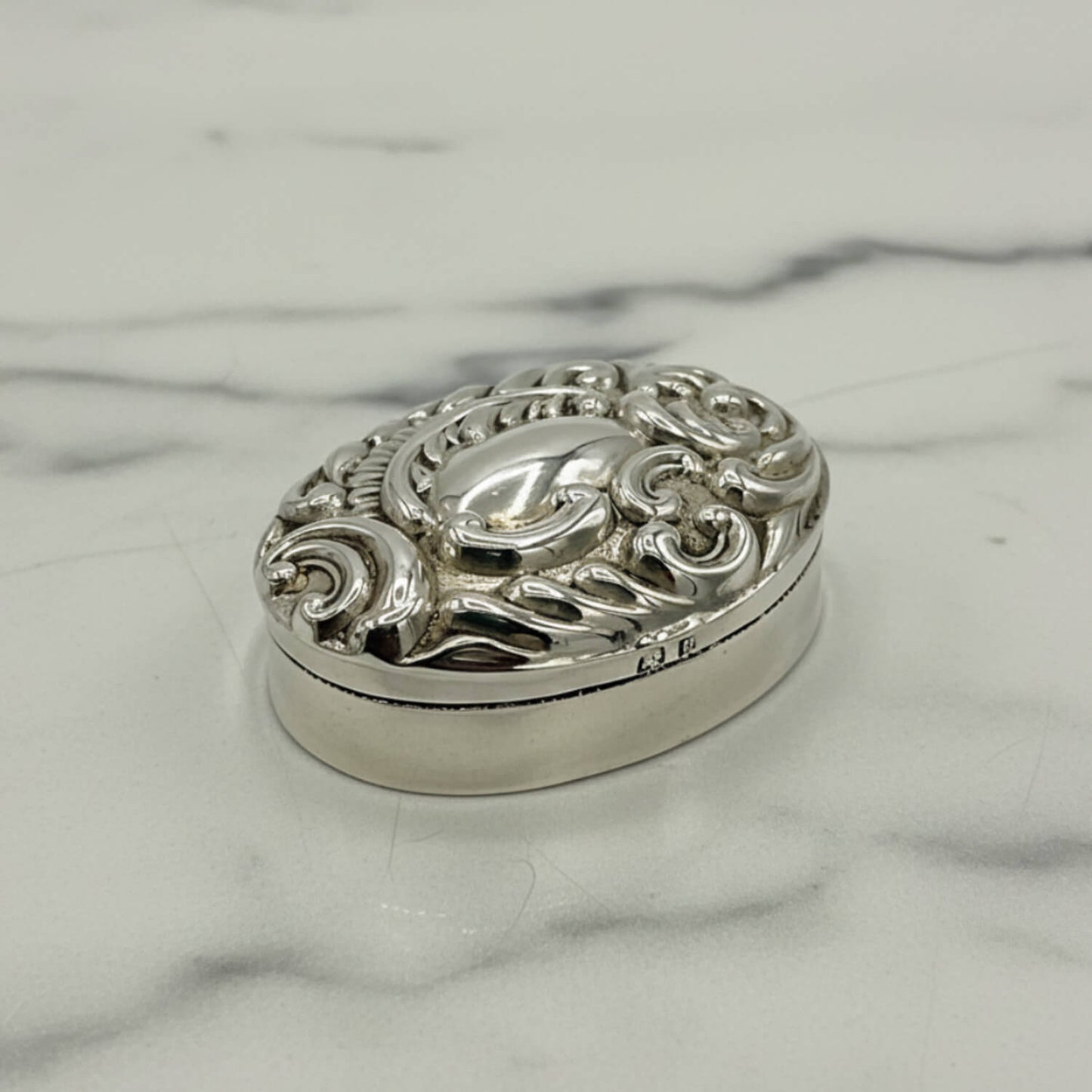Silver decorative pill box on a marble surface