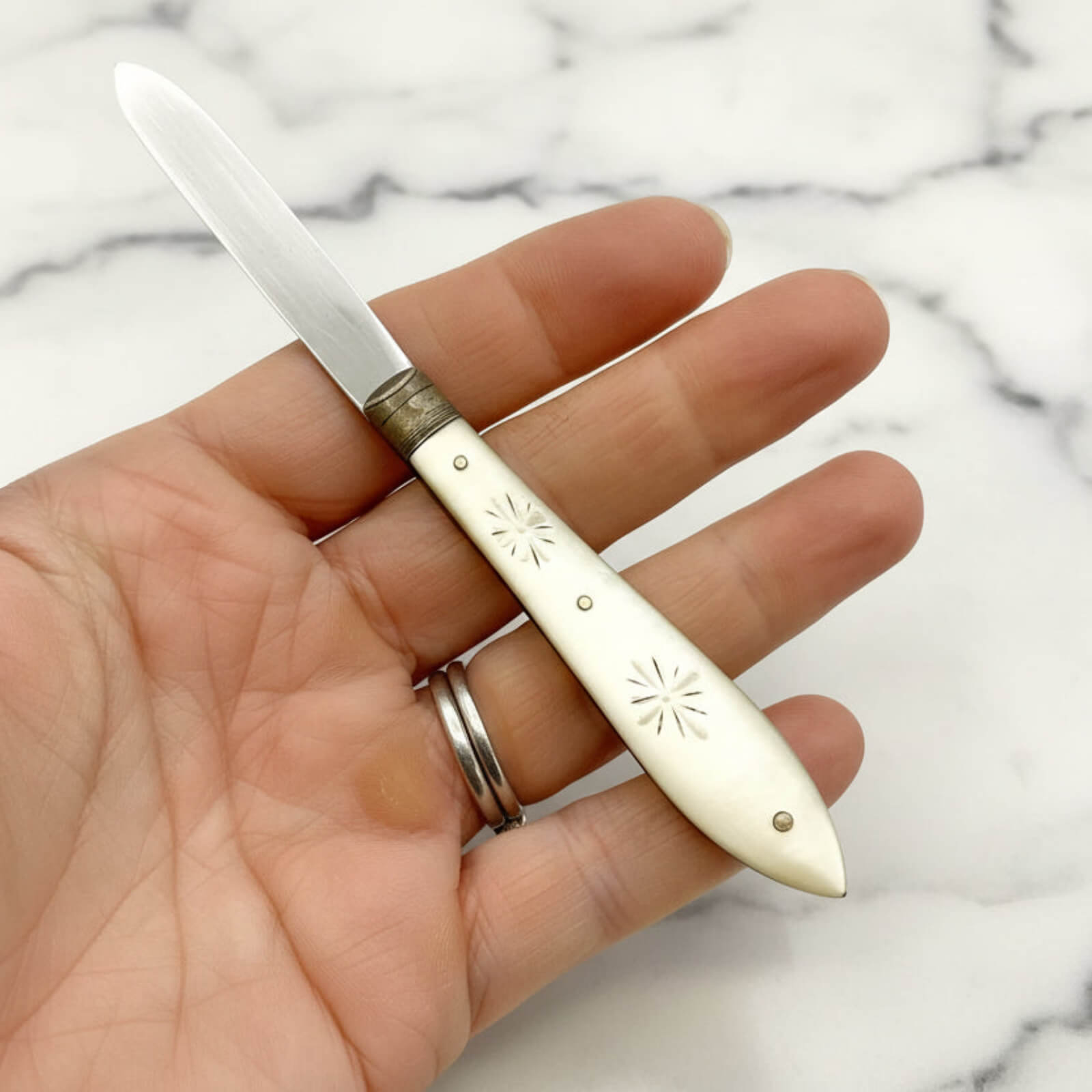 Hand holding a decorative knife with a marble background
