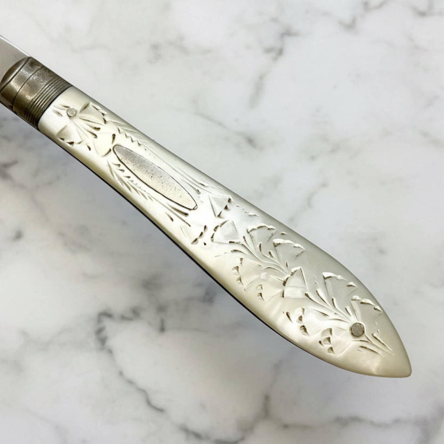 Decorative knife handle with engraved patterns on a marble background