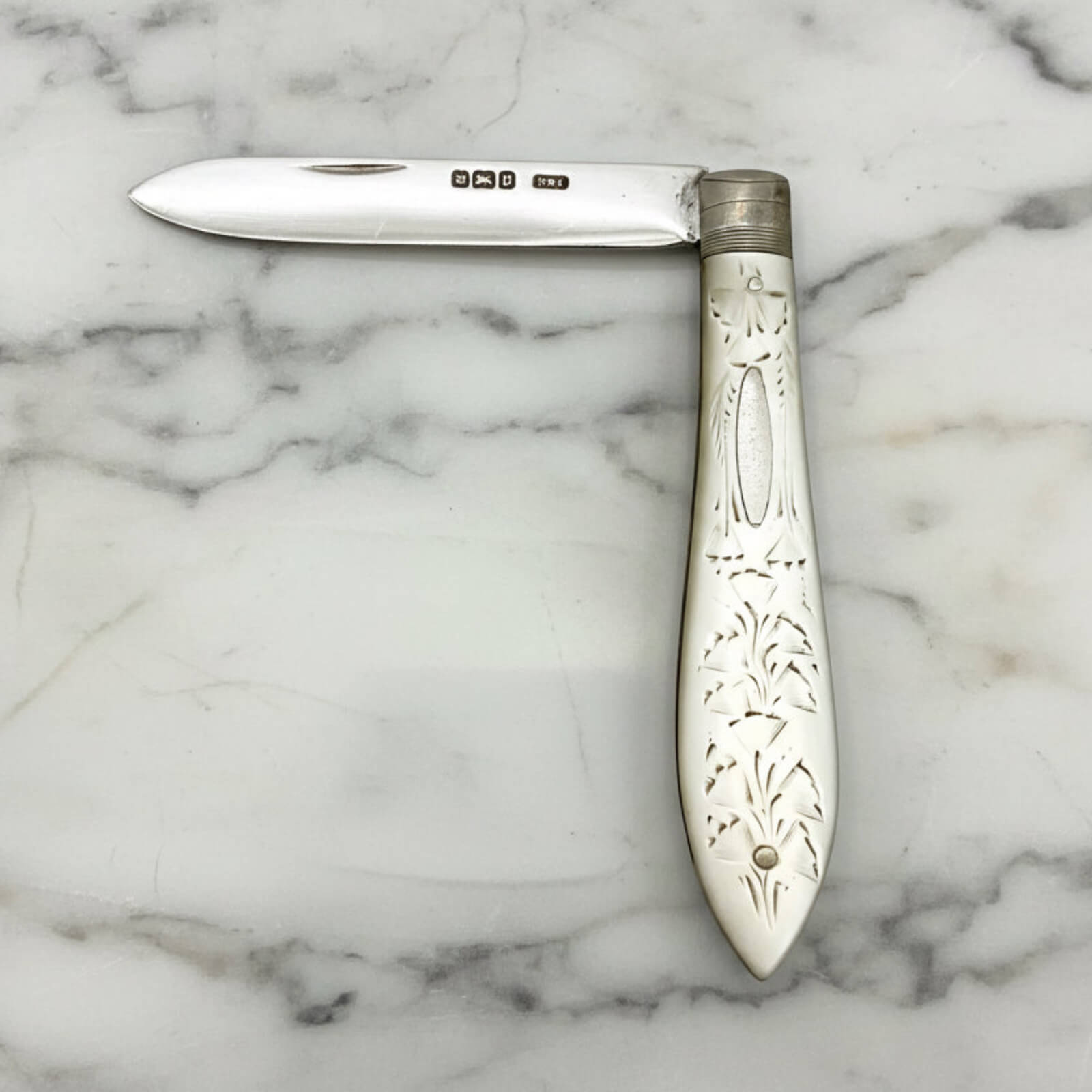 Decorative silver fruit knife on a marble surface