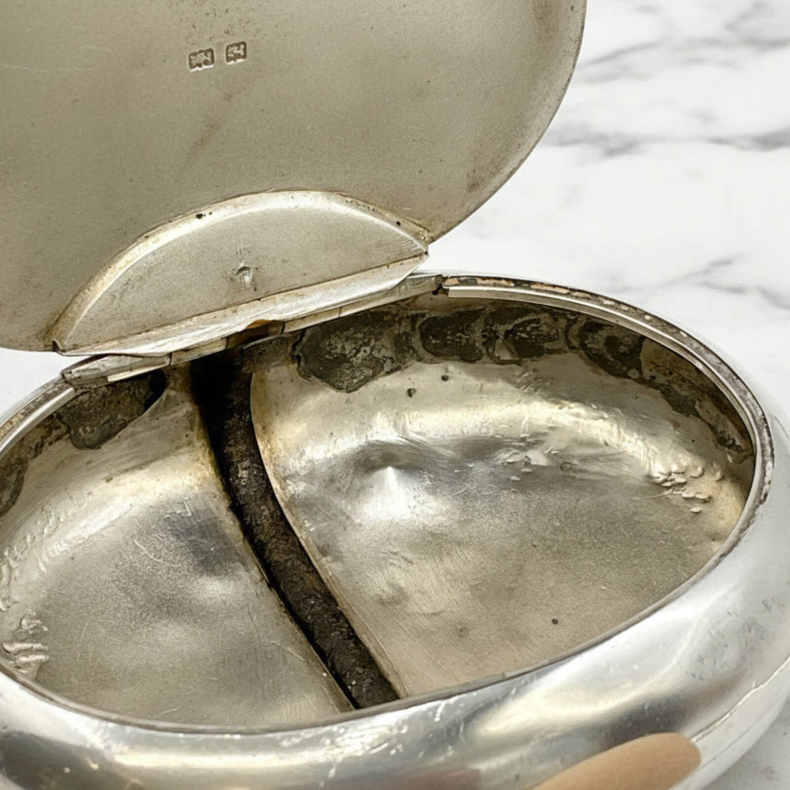 inside of silver box with a lid on a marble surface