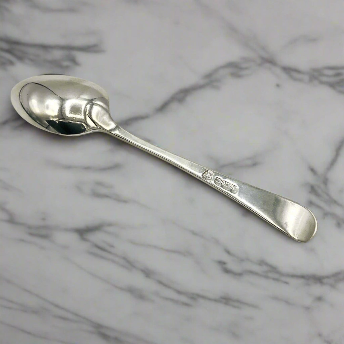 Back of antique silver teaspoon on a marble worktop 