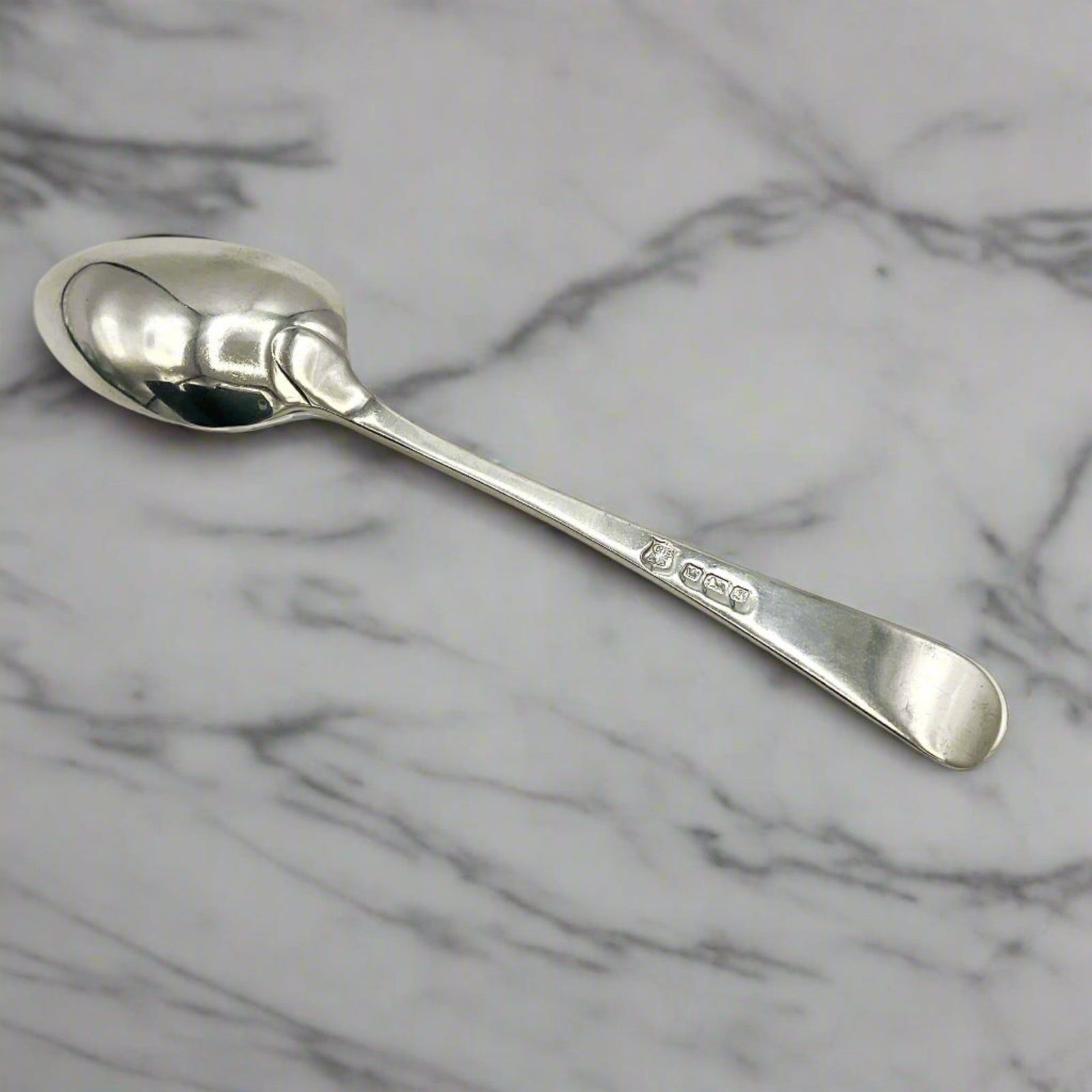 Back of antique silver teaspoon on a marble worktop 