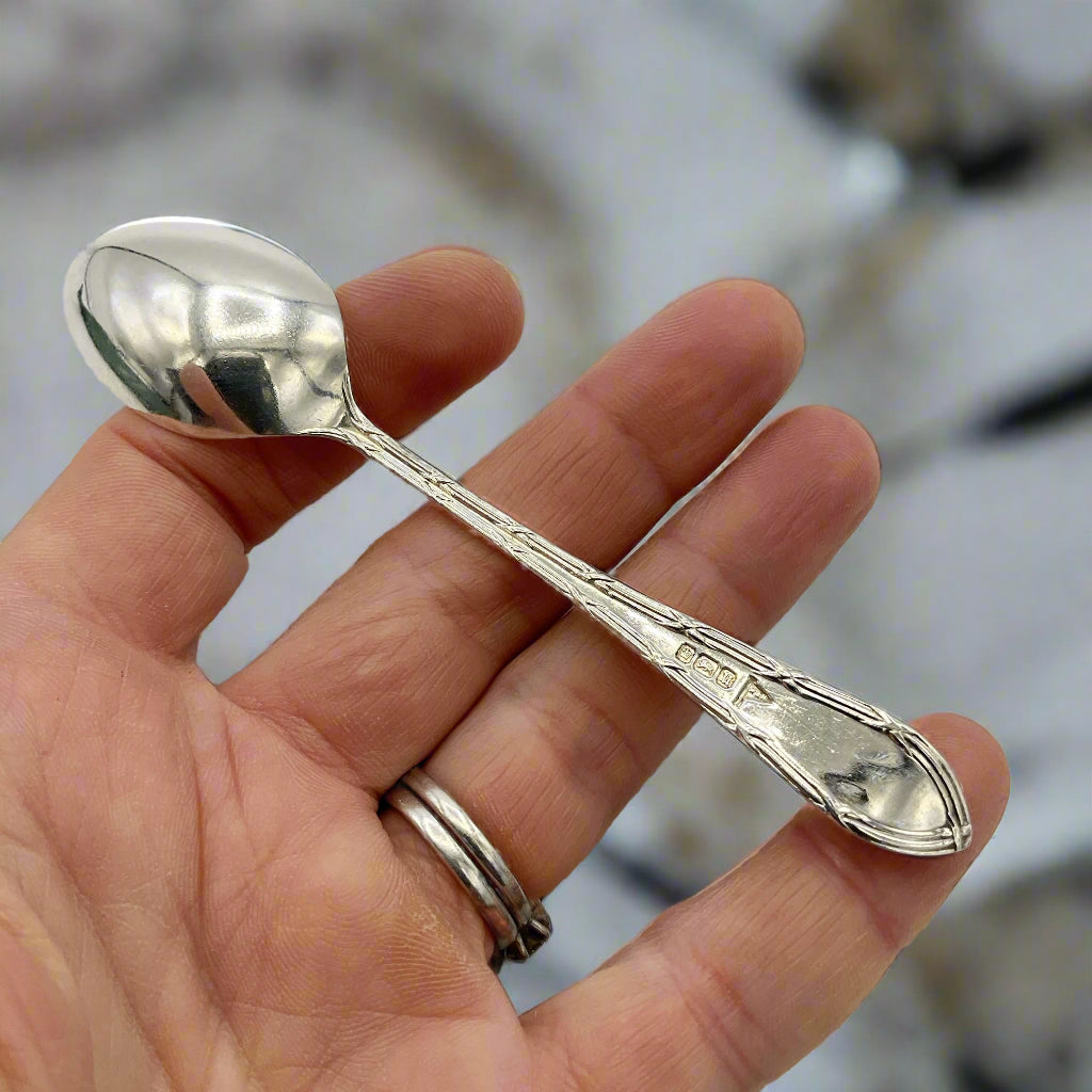 Silver spoon held between fingers against a marble worktop background