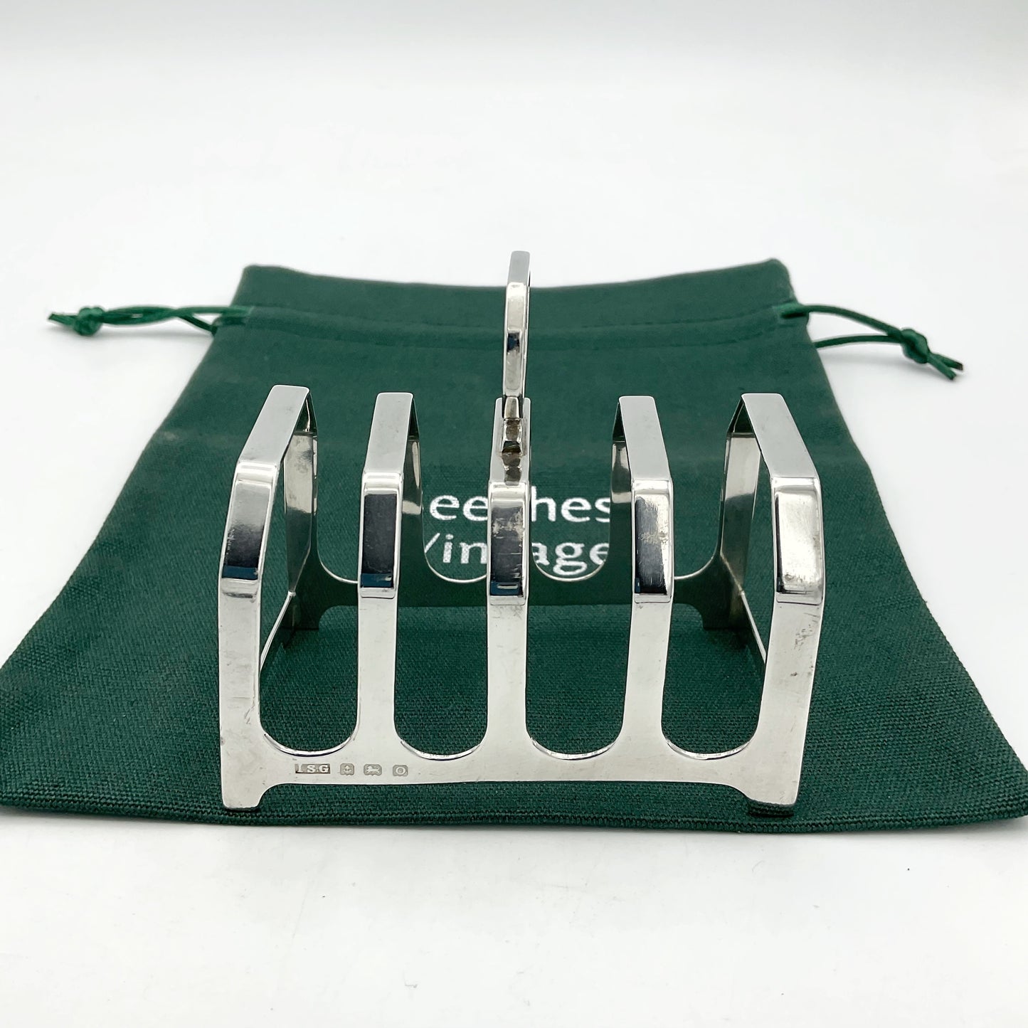 Pretty antique art deco style silver toast rack on a green cotton bag