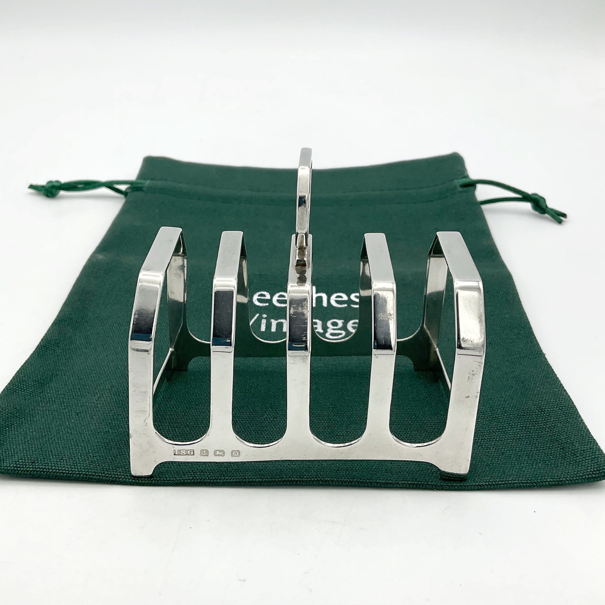 Pretty antique art deco style silver toast rack on a green cotton bag