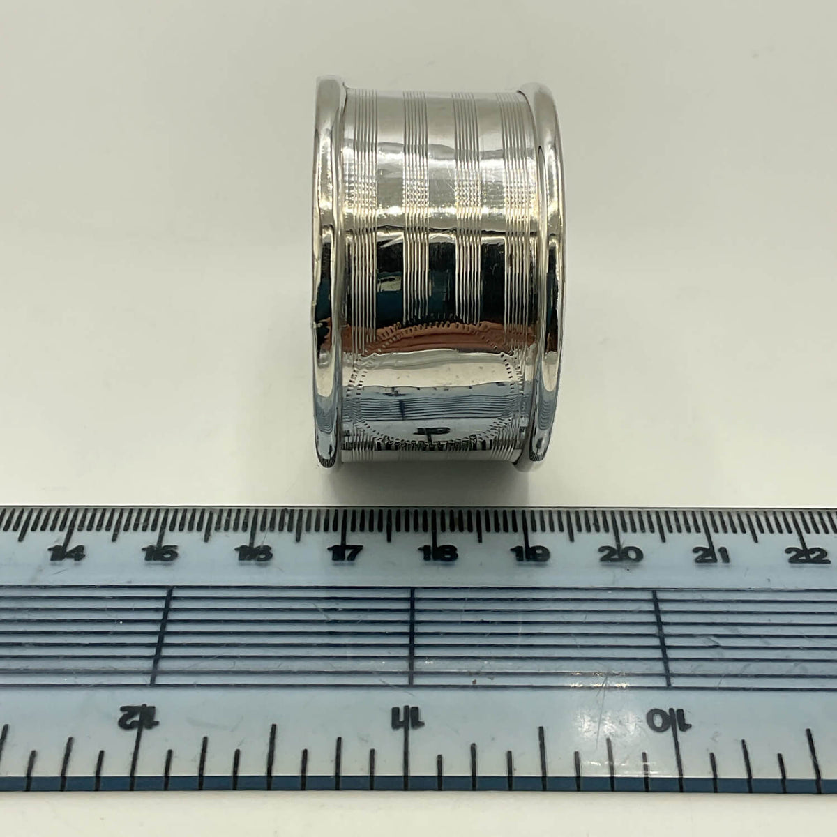 Antique 1920 Sterling Silver Napkin ring with a textured, ribbed design, shown next to a blue plastic ruler for scale on a white background.