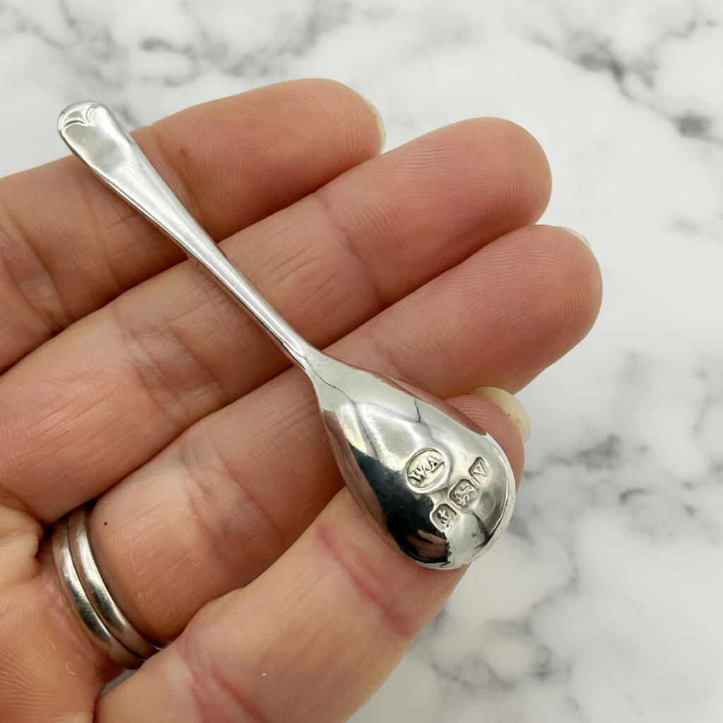 Silver spoon held in a hand with a marble background