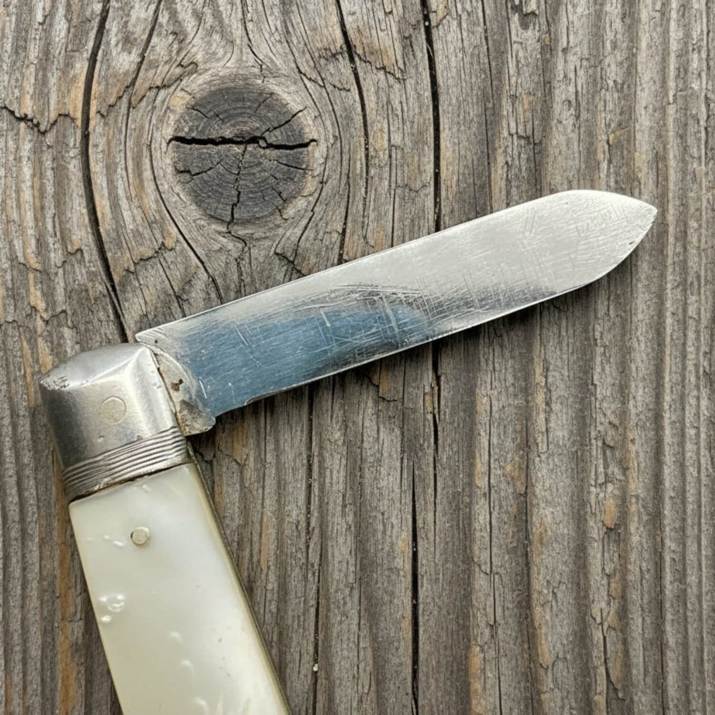 Knife with pearl handle and silver blade on a wooden background