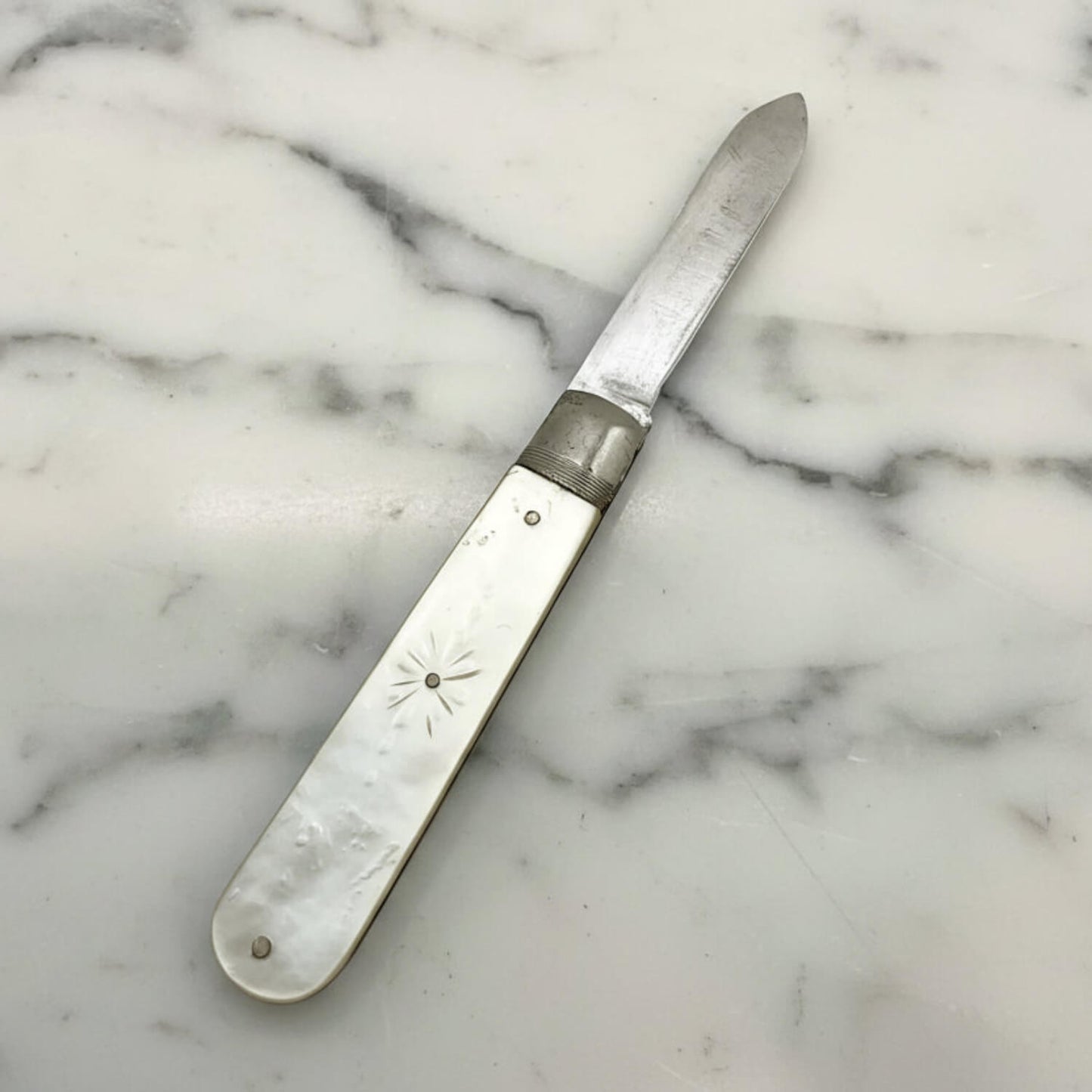 Antique fruit knife with decorative handle on a marble surface