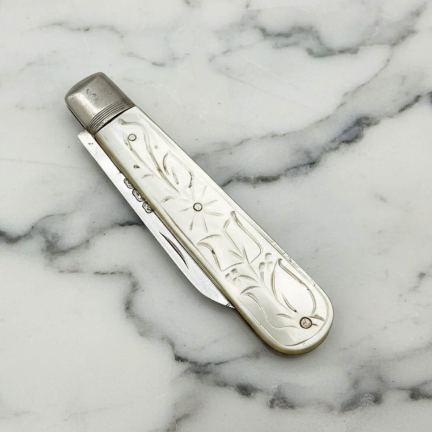 Decorative fruit knife with ornate design on a marble surface