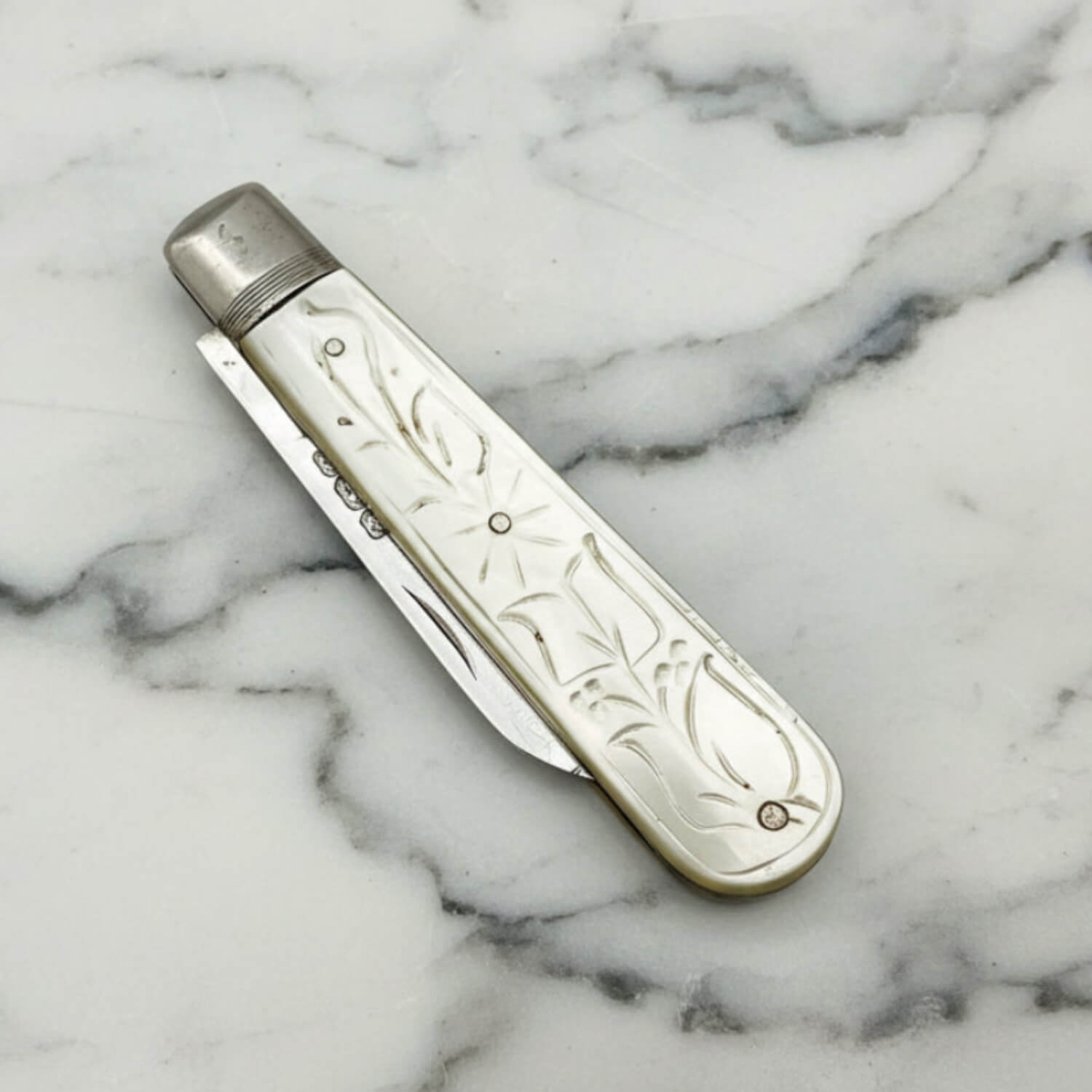 Decorative fruit knife with ornate design on a marble surface