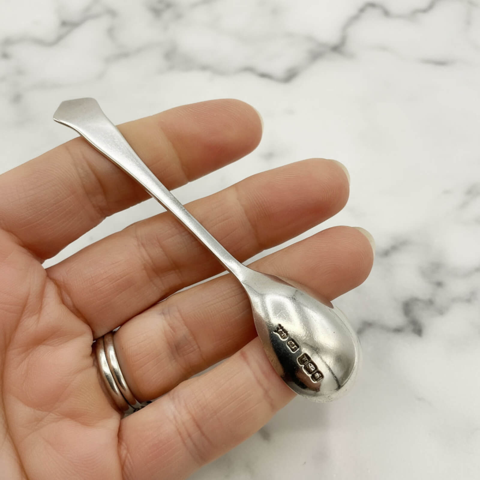 Antique Art Deco Sterling Silver Salt Spoon in a hand with marble background