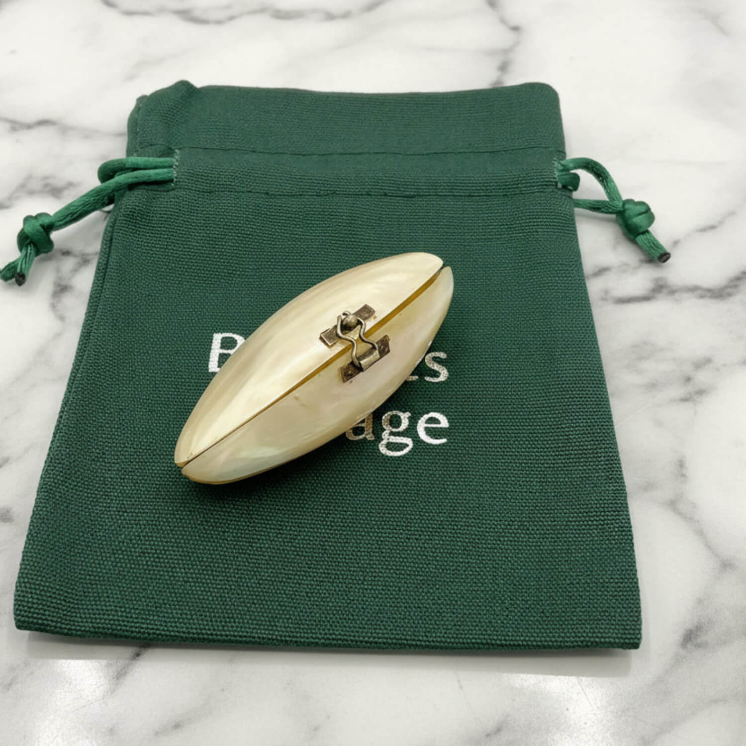 shell box on a green drawstring bag with visible text on a marble surface