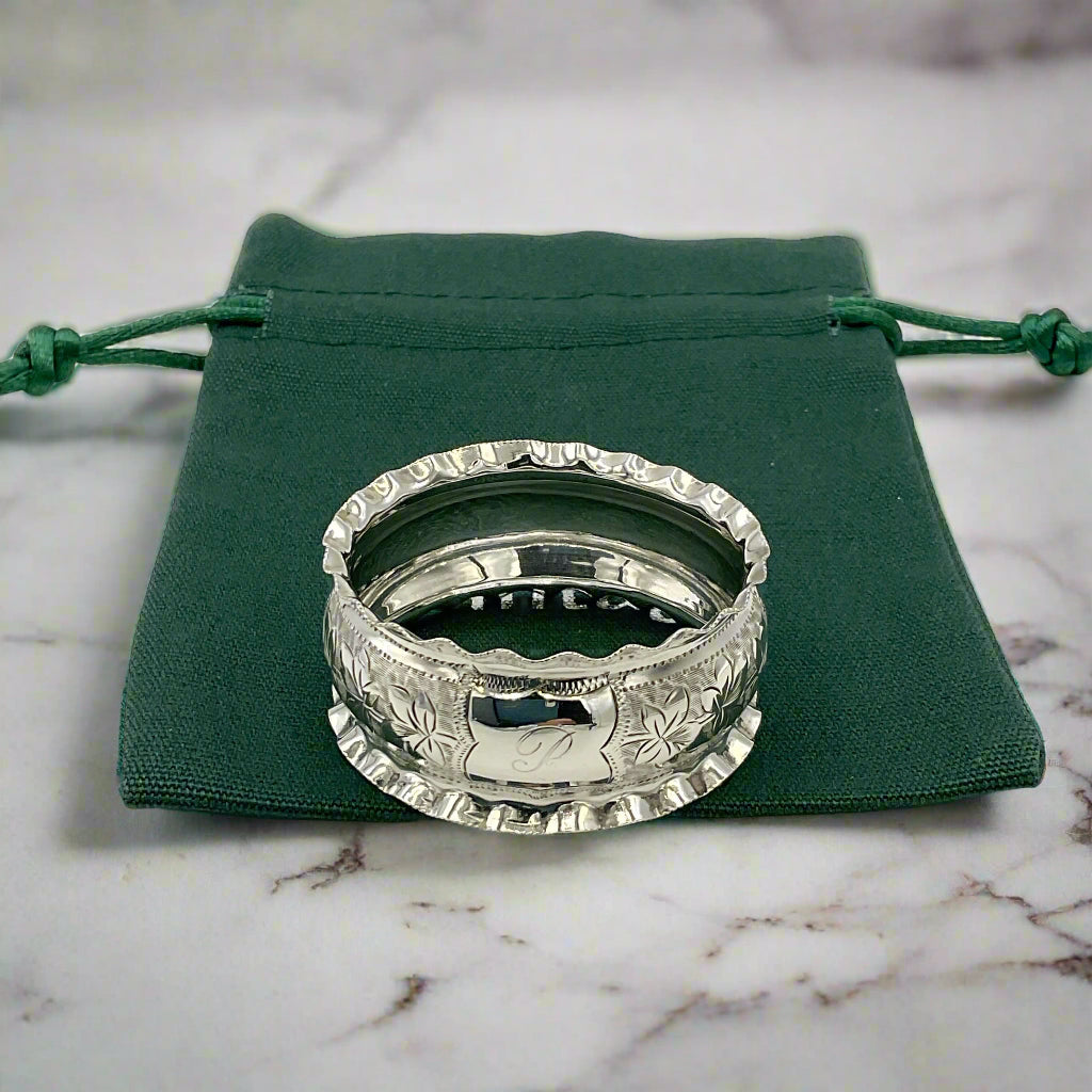 Silver ring with intricate design on a green drawstring bag on a marble worktop