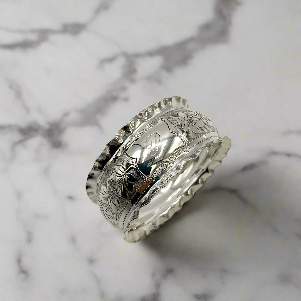 Silver ring with intricate engravings on a light marble background 