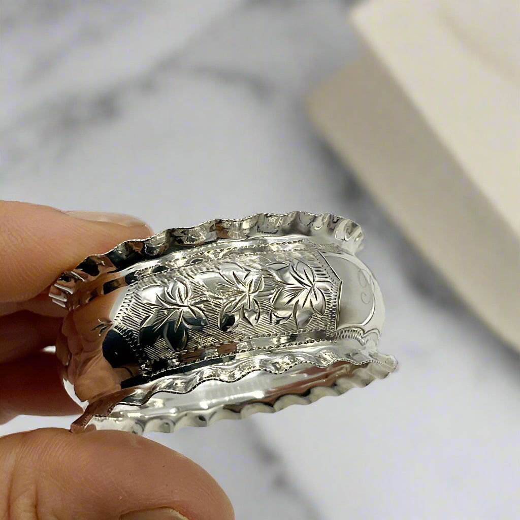 Silver napkin ring held by a hand with a marble background