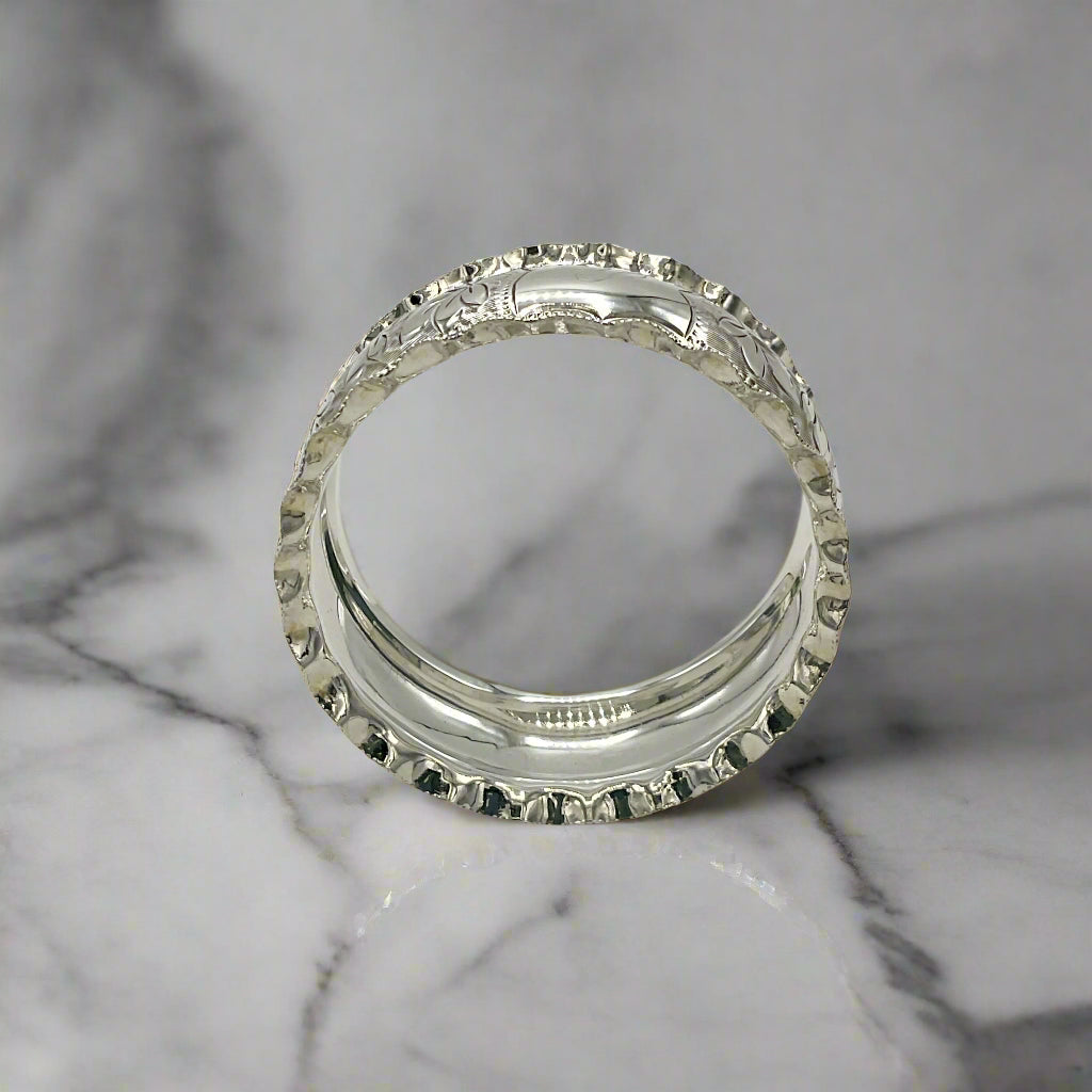 Silver napkin ring with intricate design on a marble worktop