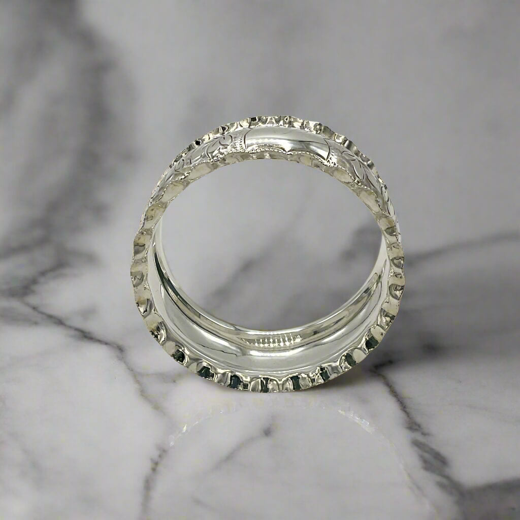 Silver napkin ring with intricate design on a marble worktop