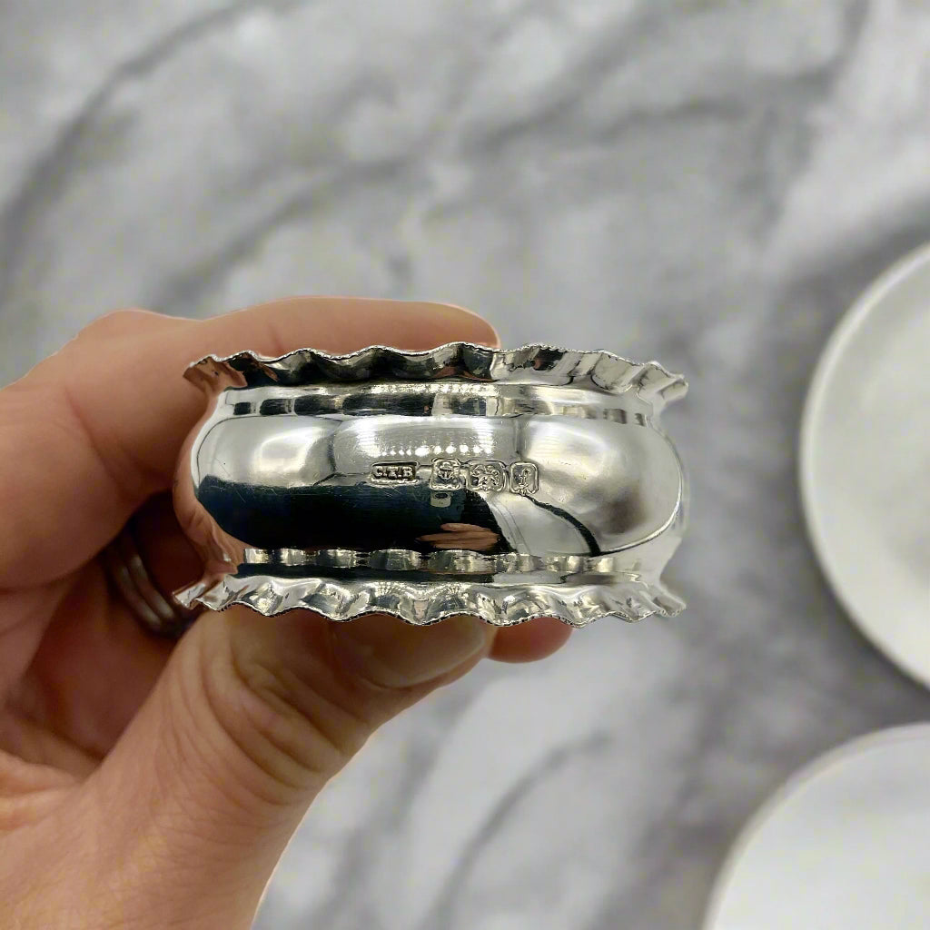 Silver napkin ring held by a hand with a marble background